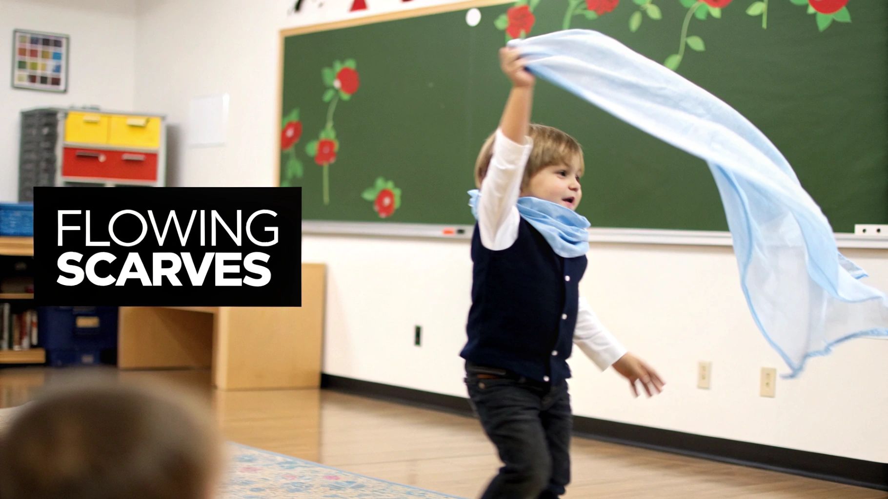 A joyful preschooler waves a light blue flowing scarf in a classroom during a movement activity.