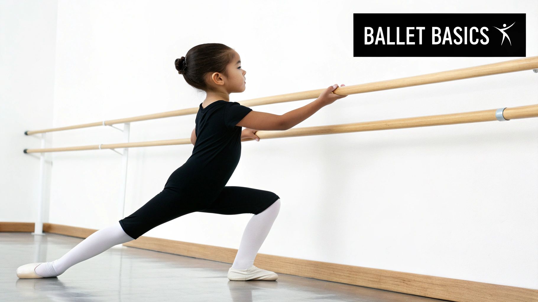 A young girl in a black leotard and white tights practices ballet stretches at a barre.