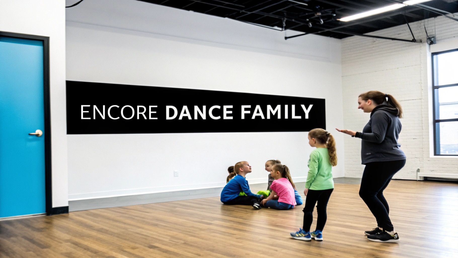 An instructor teaches young children in a bright dance studio with an “Encore Dance Family” banner.