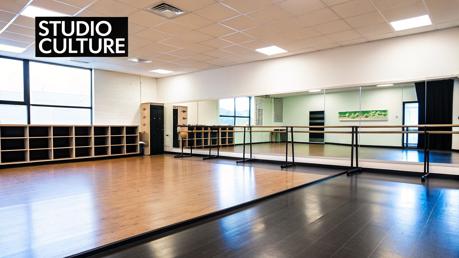 Empty dance studio with large mirrors, ballet barres, and a two-tone floor.