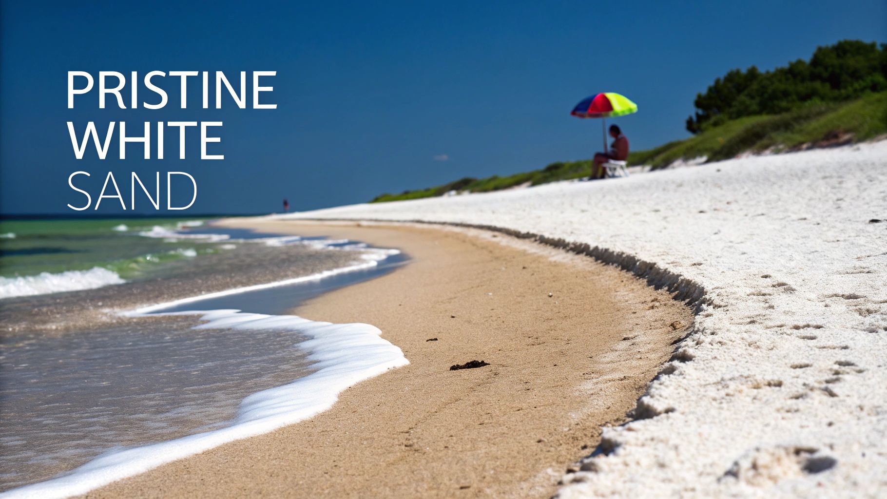A scenic view of a pristine white sand beach with gentle waves and a person under an umbrella.