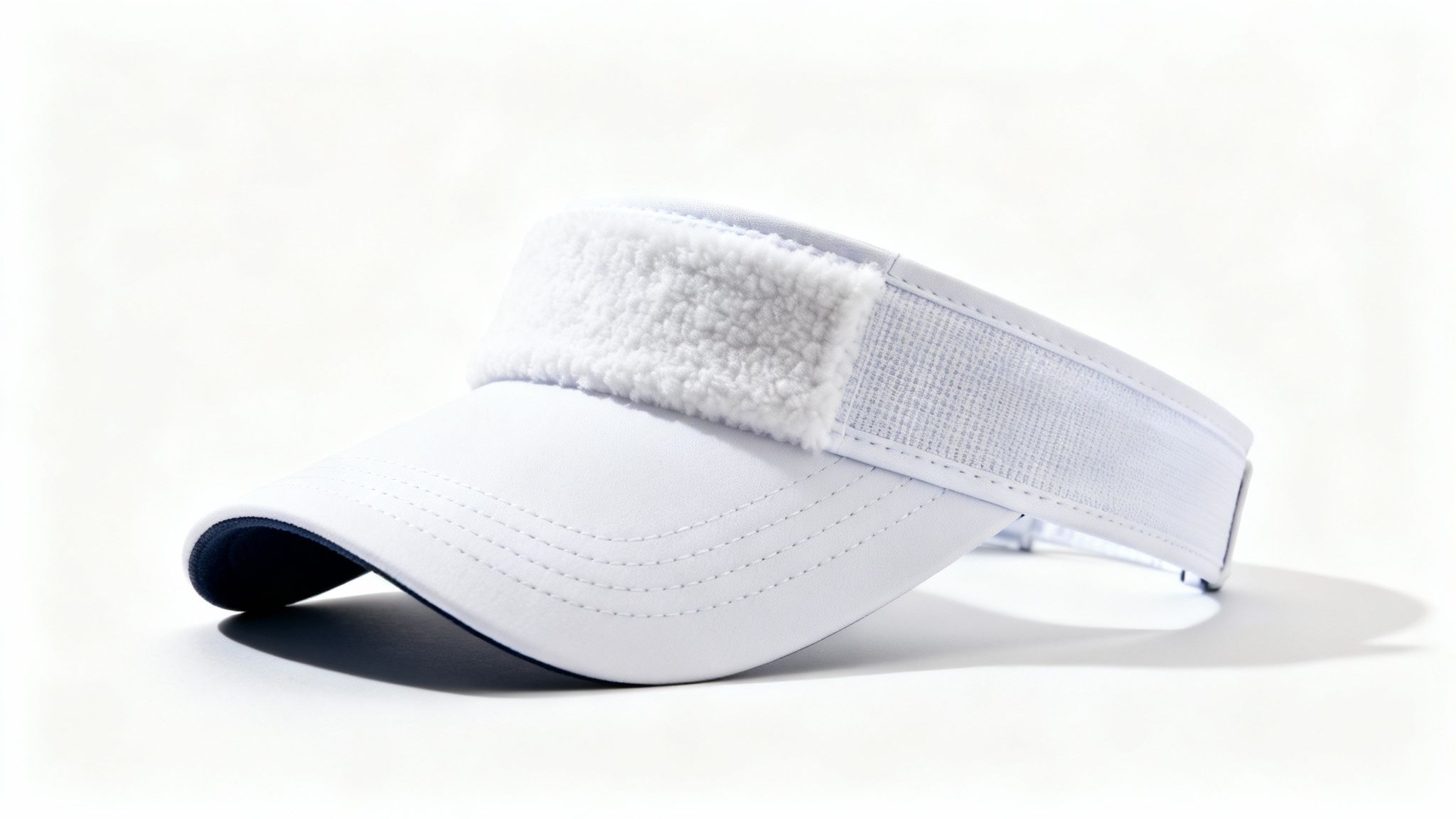 White golf visor with navy blue underside and adjustable velcro strap on white background