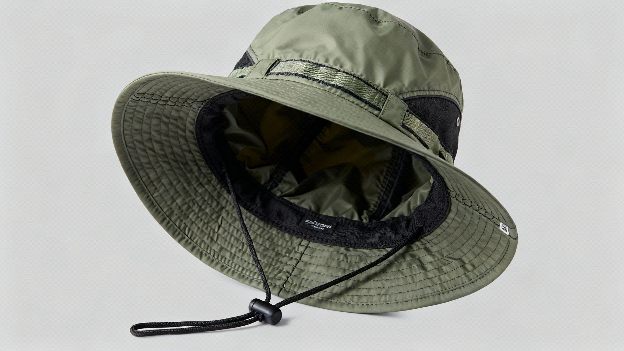 An olive green boonie hat with a wide brim and adjustable chin strap, displayed on a light background.