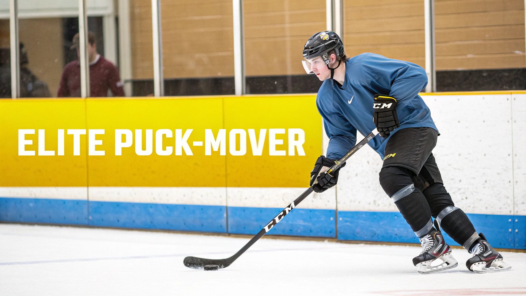 Hockey player in blue practice jersey skating with puck during training session on ice rink