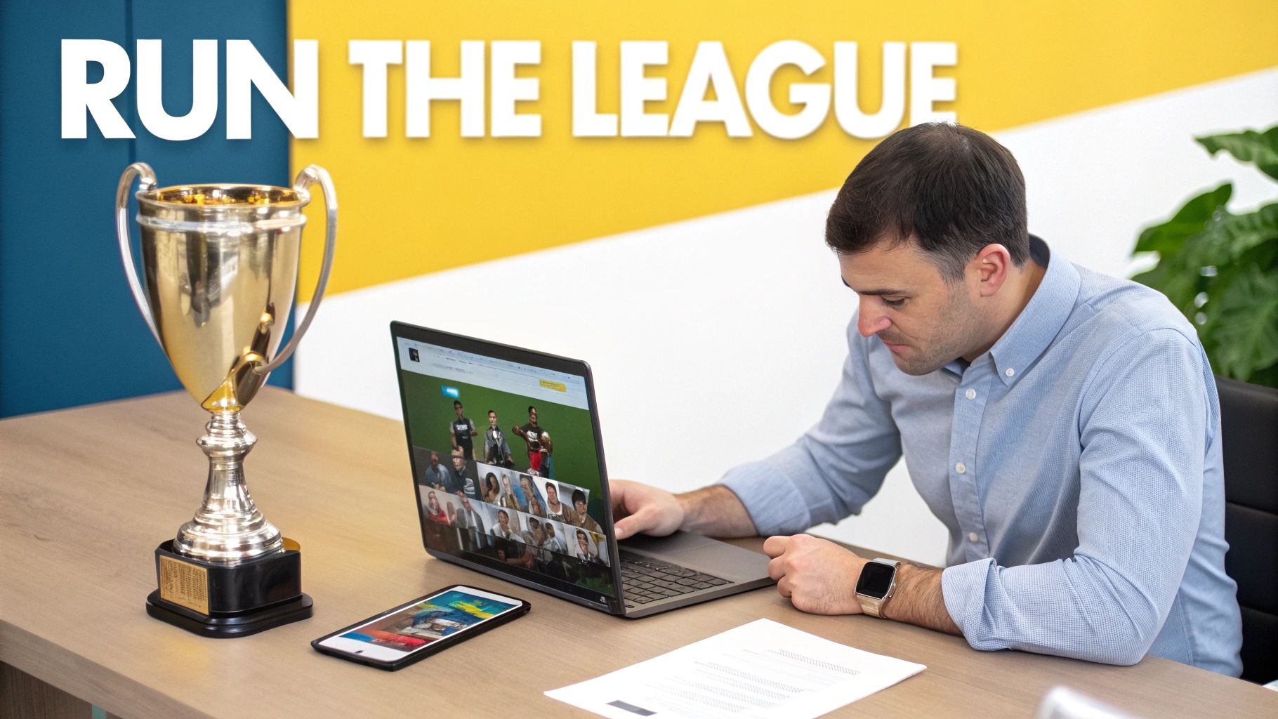 Man at a desk looking at a laptop showing a video conference, with a trophy and 'RUN THE LEAGUE' sign.