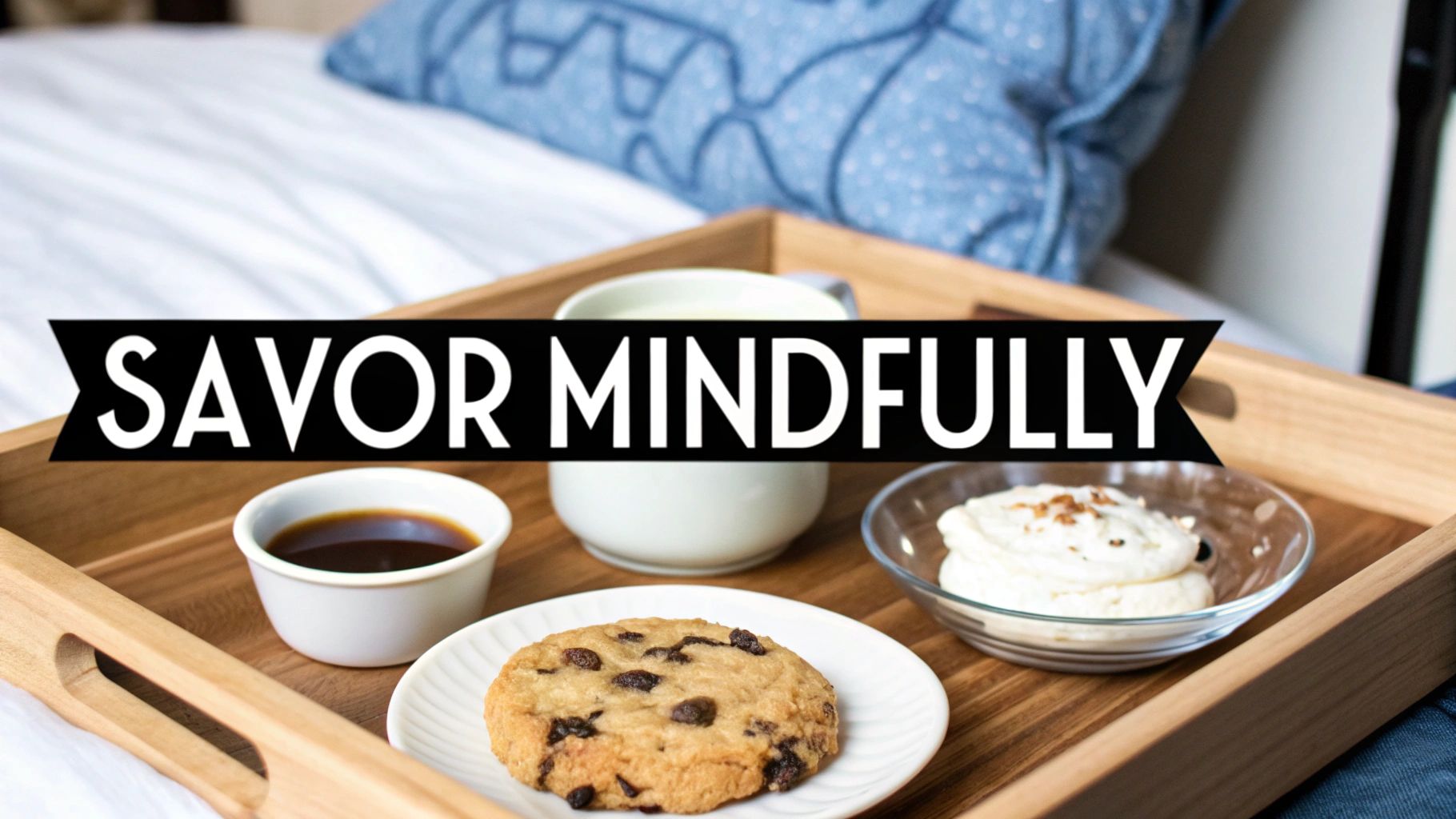 A wooden breakfast tray on a bed with a chocolate chip cookie, a cup of coffee, and whipped cream, featuring 'SAVOR MINDFULLY' text.