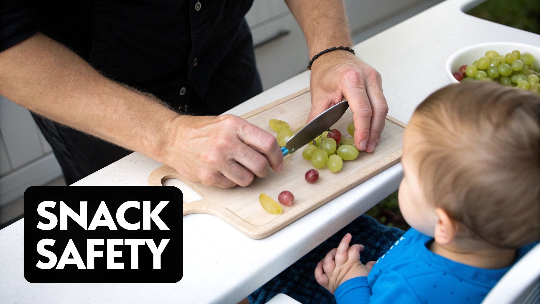 A person cuts grapes on a wooden cutting board, preparing a safe snack for a toddler.