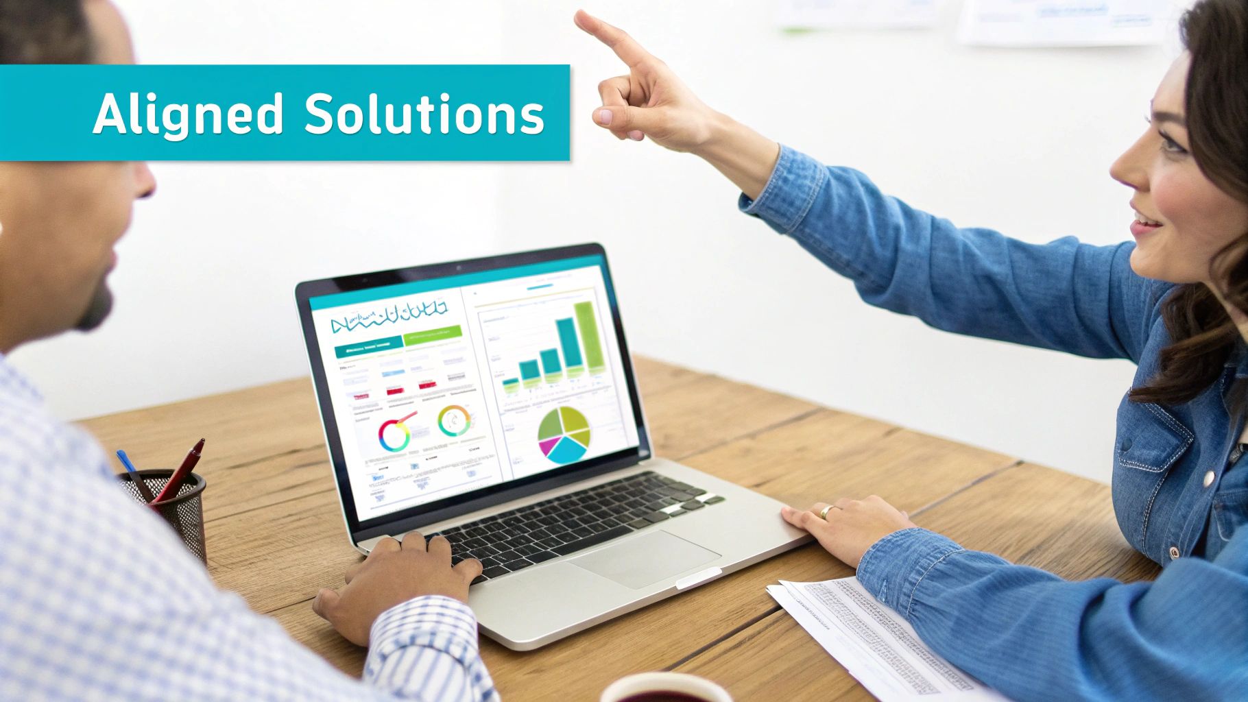 Two professionals collaborate on a laptop, analyzing data charts and graphs for business solutions.