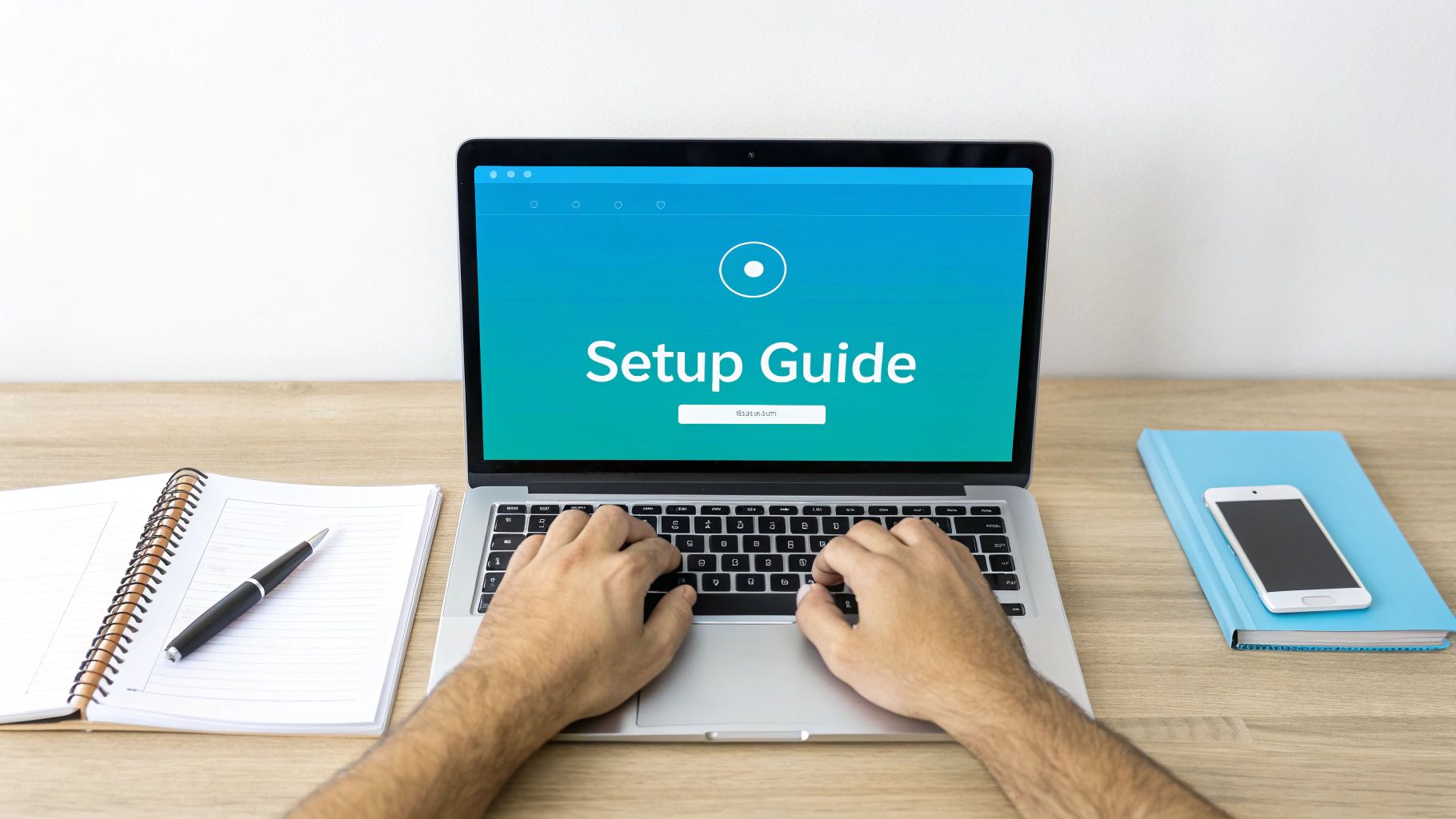 A person typing on a laptop displaying 'Setup Guide' on a wooden desk with a notebook and phone.