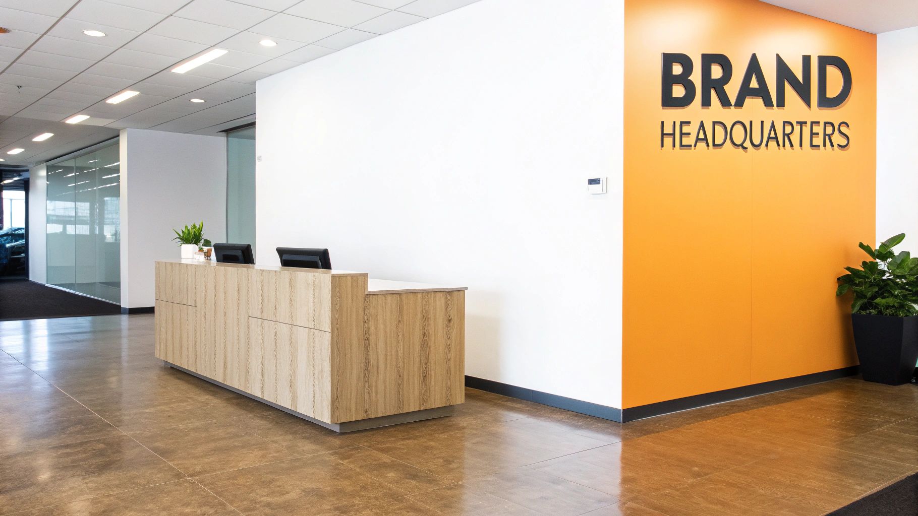 Modern office reception area with a wooden desk, dual monitors, and a prominent 'BRAND HEADQUARTERS' sign.