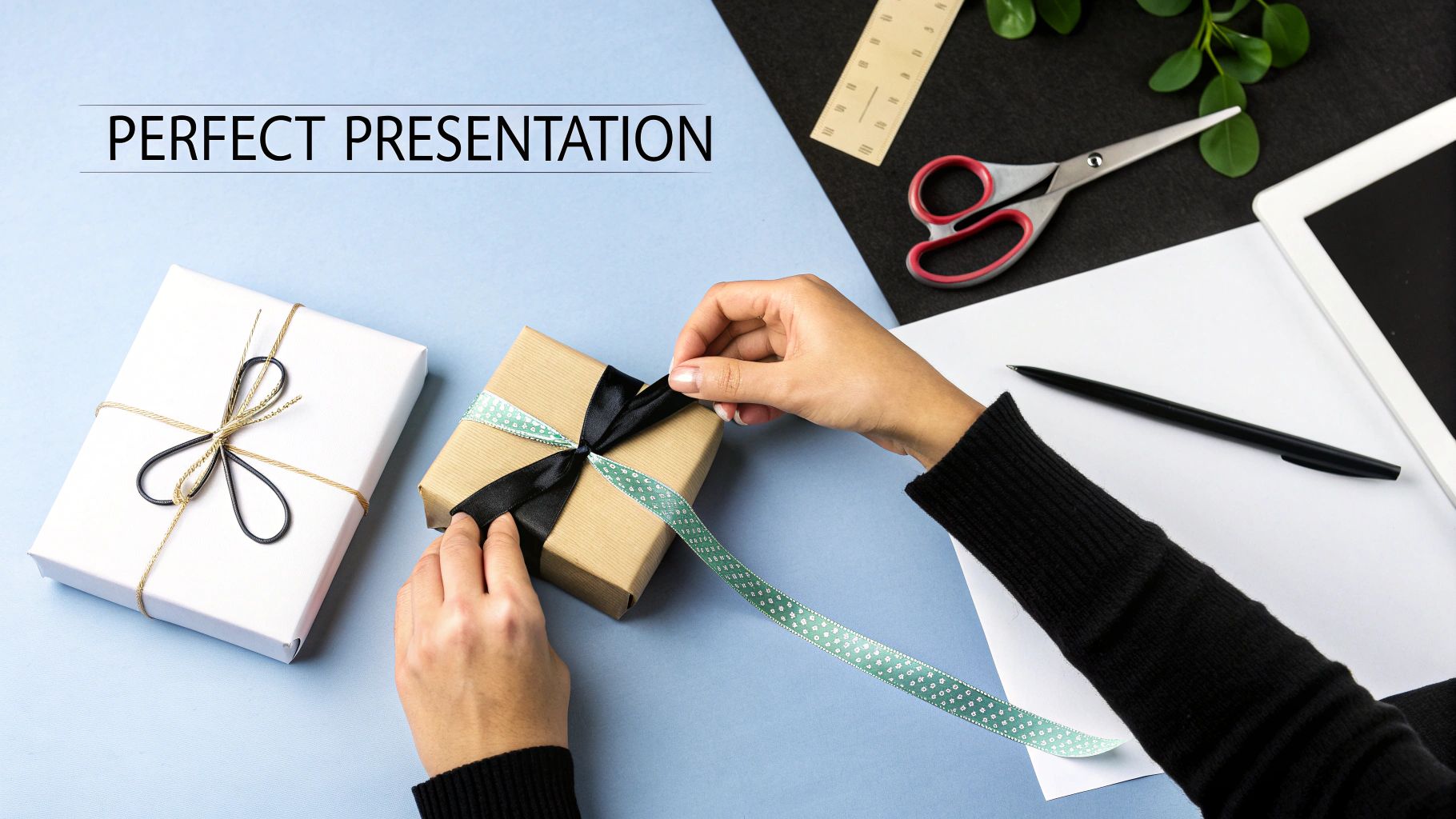 Overhead shot of hands wrapping a brown gift box with black and green ribbon.