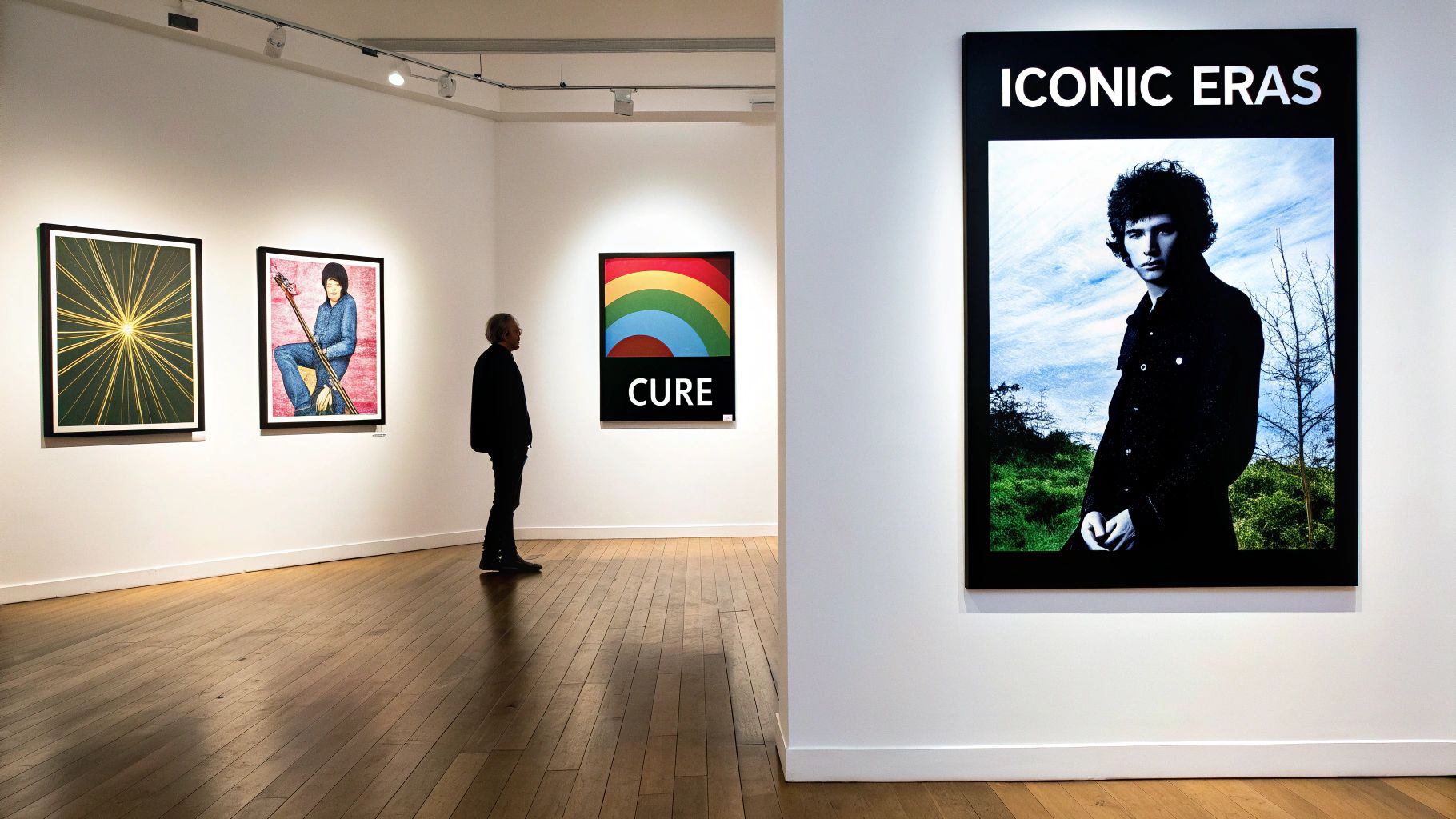 A man views art including 'CURE' and 'ICONIC ERAS' posters in a contemporary gallery.