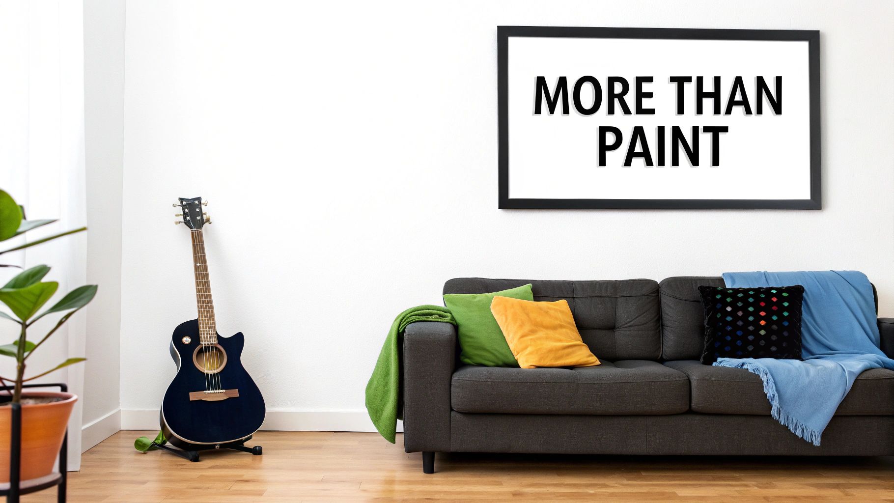 A modern living room with a grey sofa, colorful pillows, an acoustic guitar, and "MORE THAN PAINT" framed art.