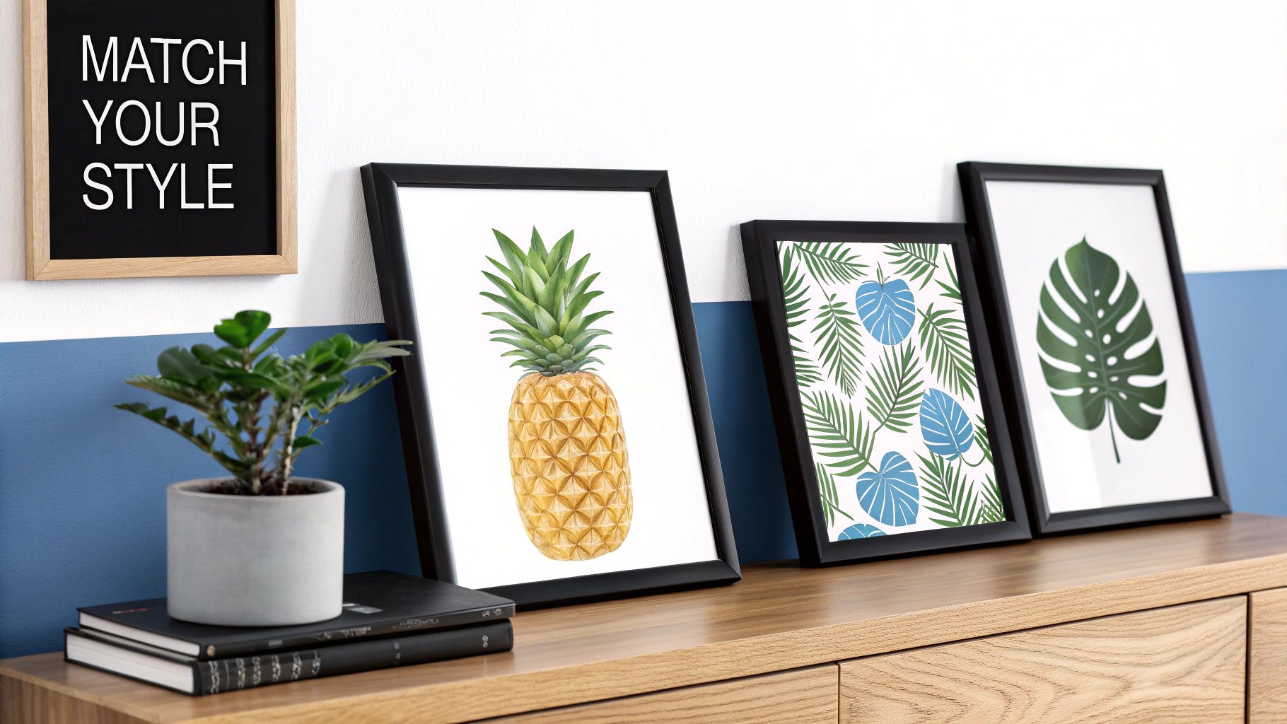 Three framed tropical prints, a potted plant, and a 'MATCH YOUR STYLE' sign on a wooden cabinet.