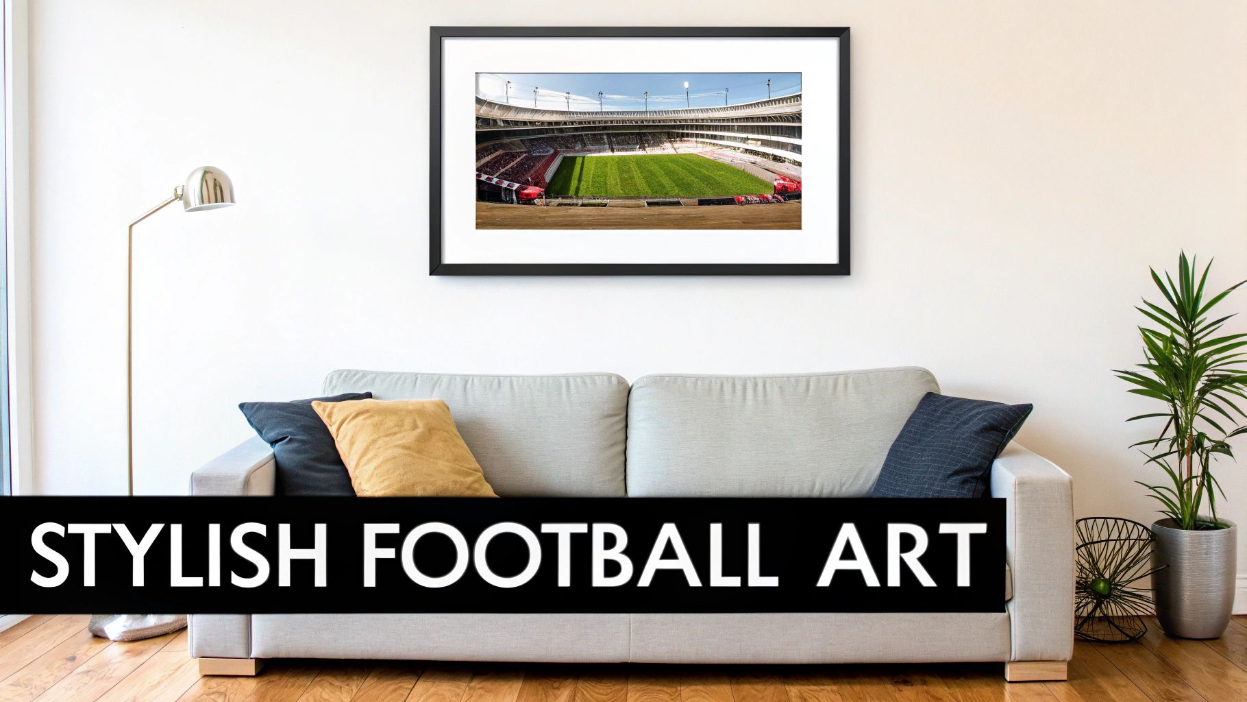 A modern living room with a gray sofa, floor lamp, plant, and a framed football stadium art print.