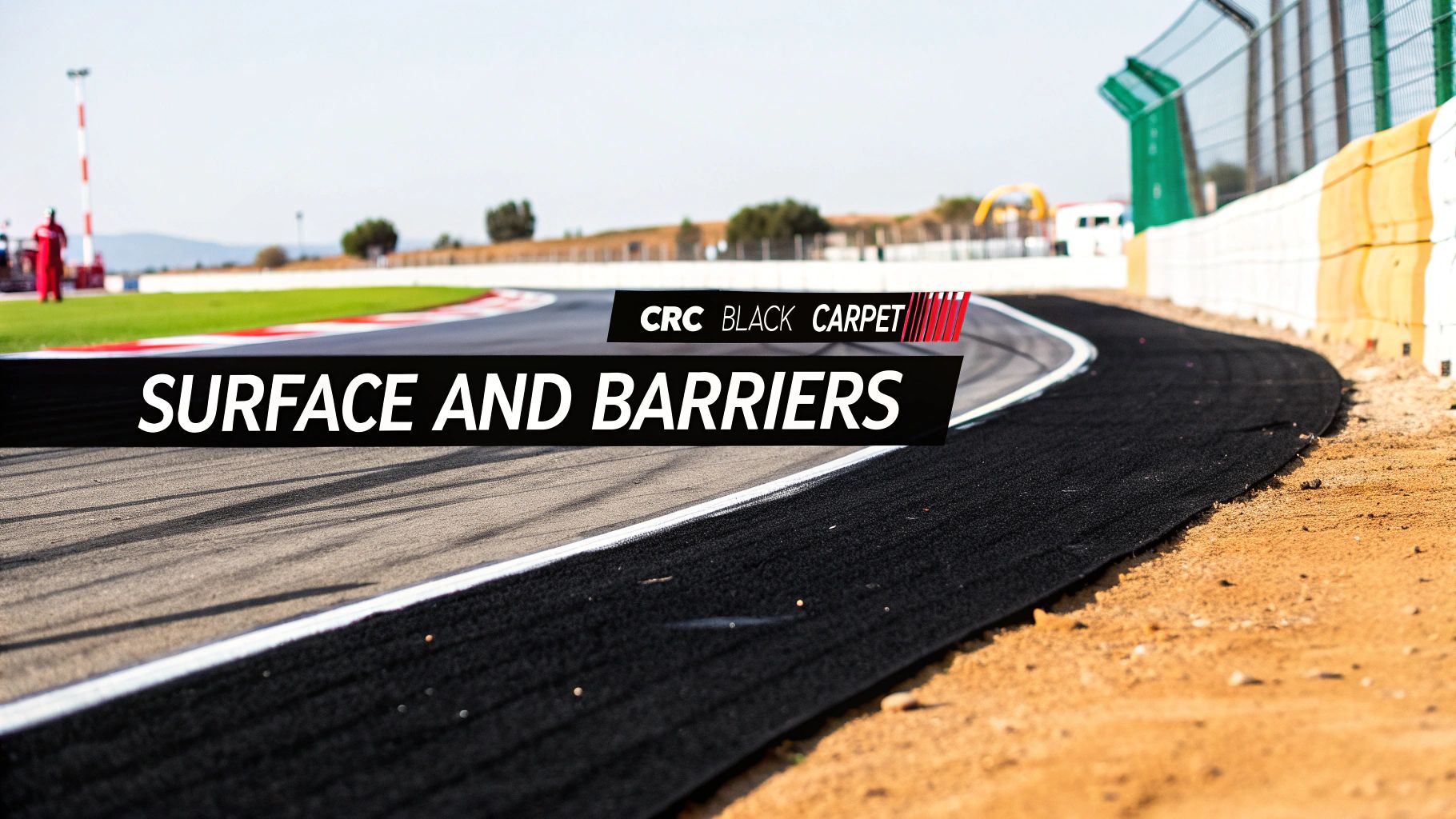 A close-up view of a race track's asphalt surface, black barriers, and white lines.