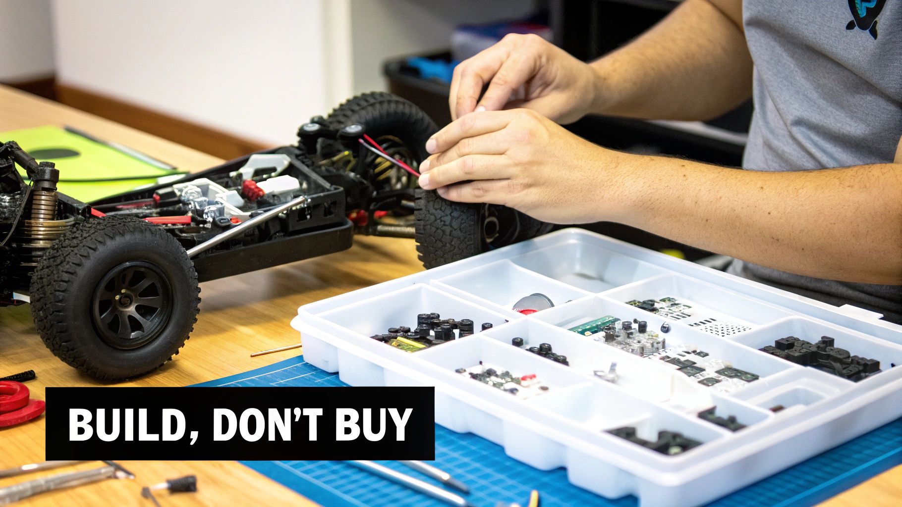 A person's hands meticulously assemble an RC car, with various parts and tools on a workbench.