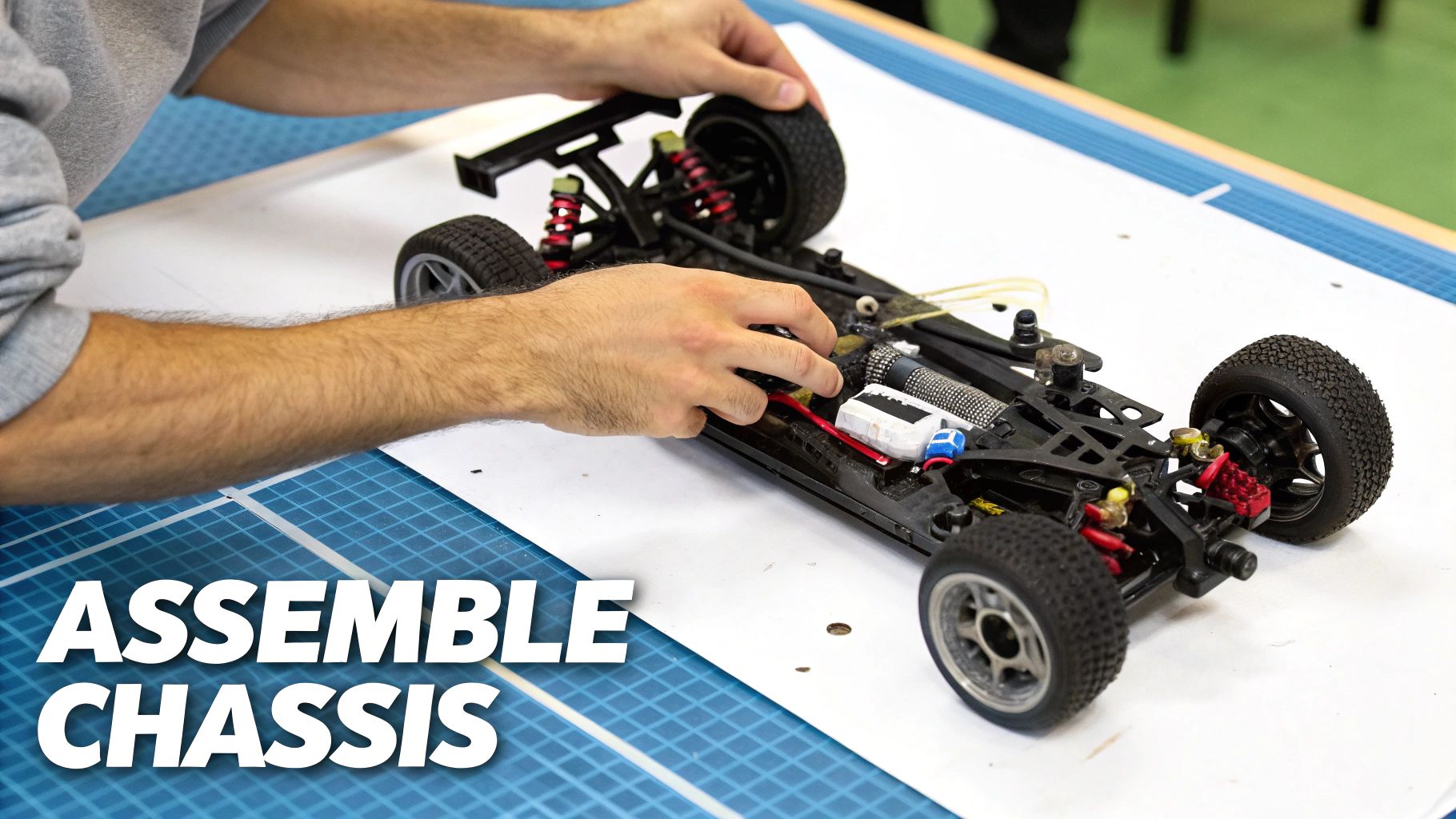 A person's hands are busy assembling the black chassis of a remote control car on a white table with a blue mat.