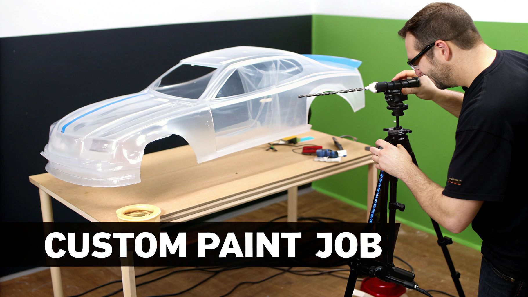 A man drills into a clear RC car body on a workbench, preparing it for a custom paint job.
