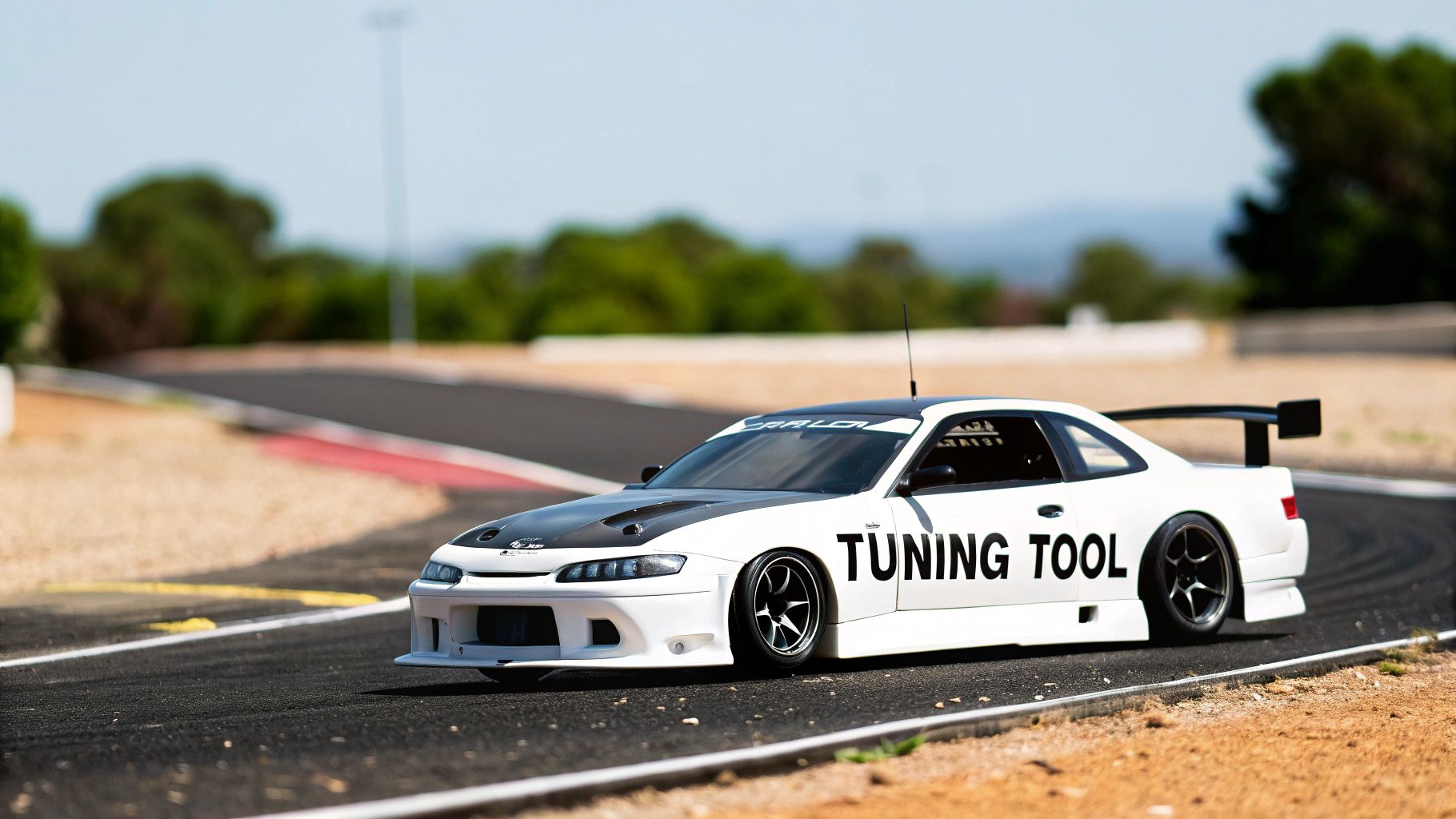 A detailed white and black 1:10 scale RC car, with "TUNING TOOL" text, on a race circuit.