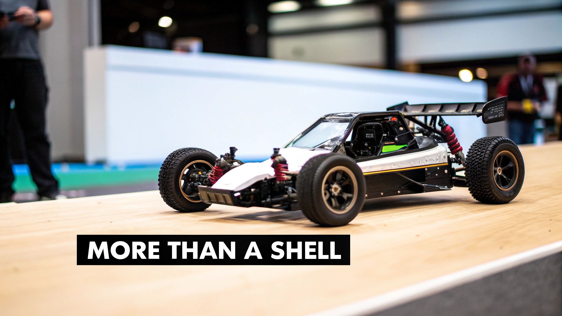 A detailed black, white, and red remote-controlled buggy with visible chassis and suspension on a wooden surface.