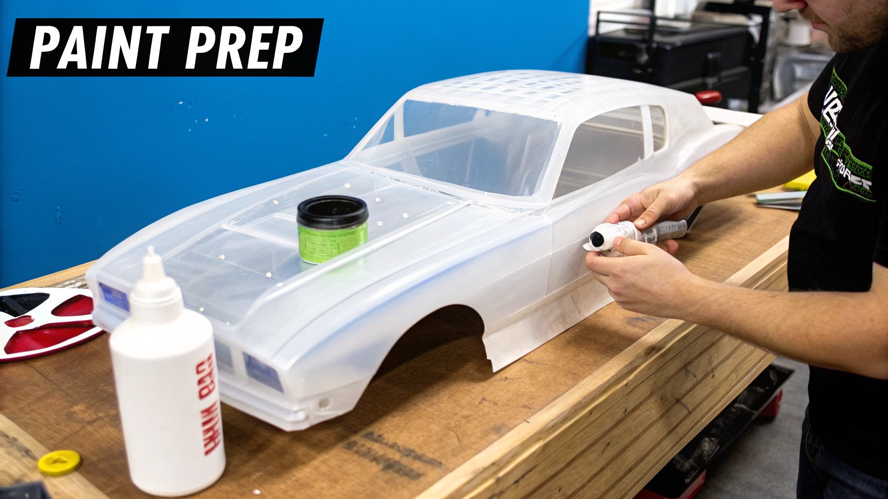 Person's hands carefully prepare a translucent RC car body for painting on a wooden table.