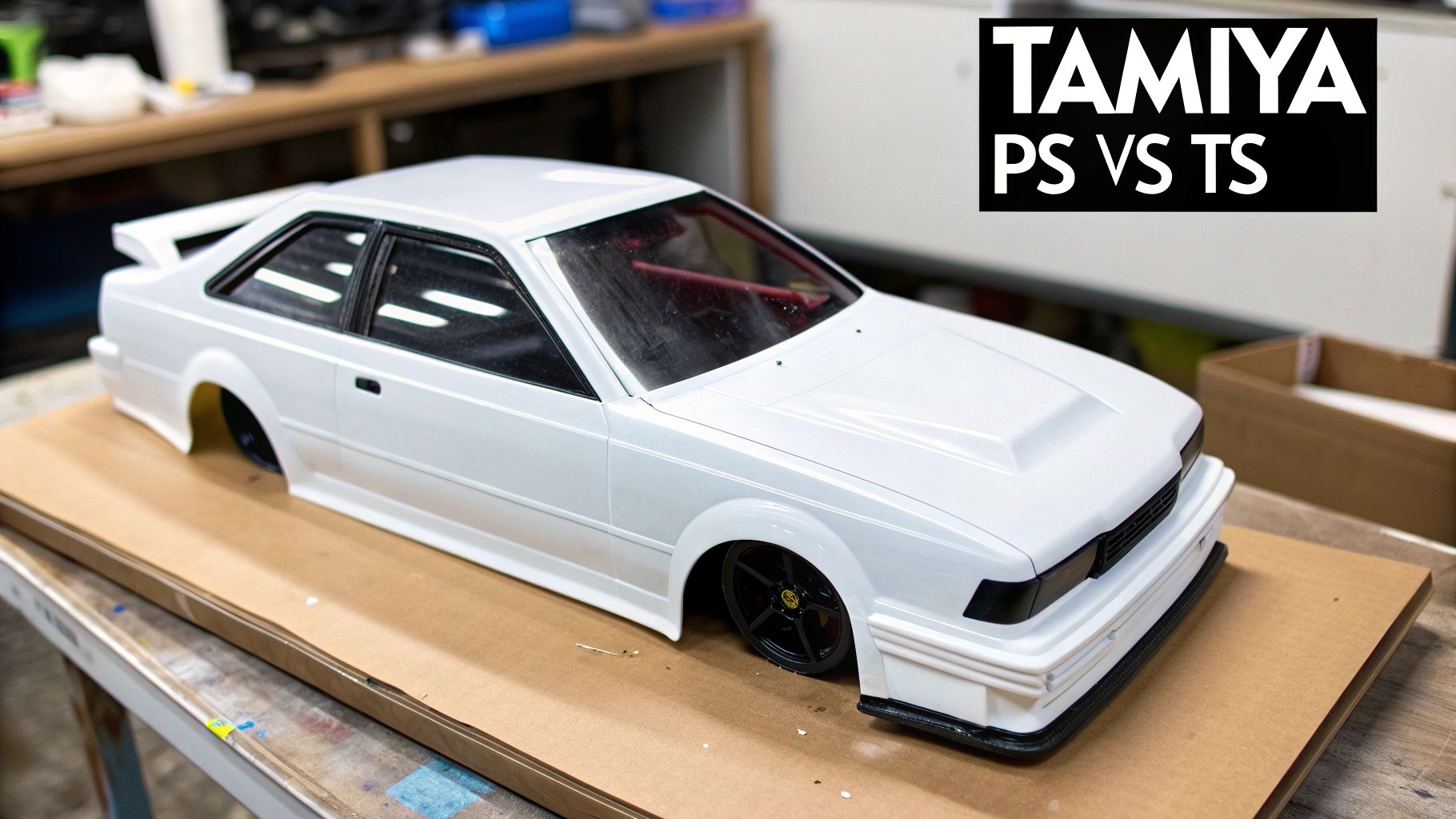 A detailed white Tamiya RC car body, featuring black wheels and a red interior, rests on cardboard.