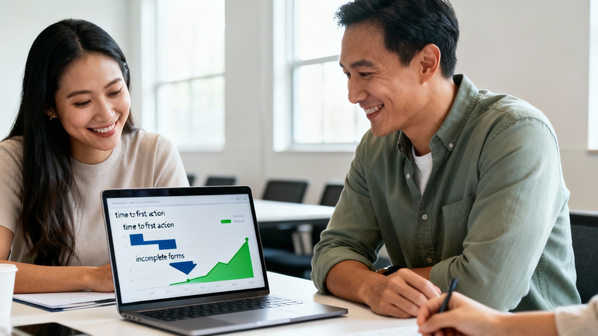 Two smiling professionals analyze a performance graph on a laptop during a collaborative meeting.