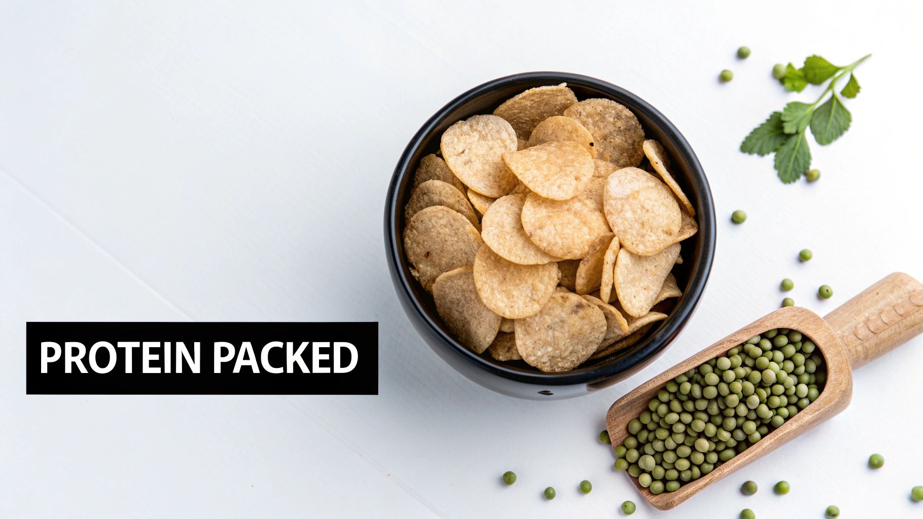 A black bowl filled with protein-packed crisps, green peas, and a green sprig on a white surface.