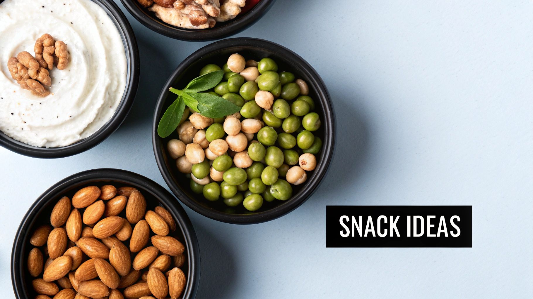 Top view of bowls with healthy snack ideas including yogurt with walnuts, peas, chickpeas, and almonds.