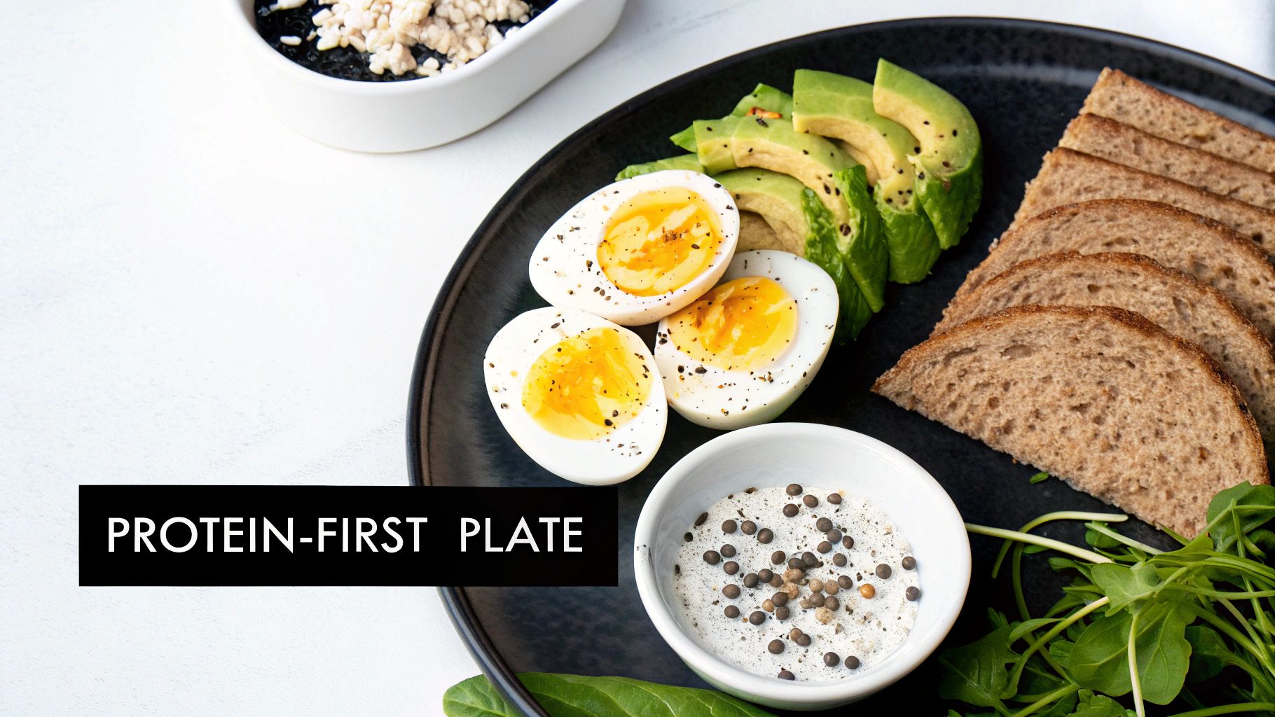 A black plate featuring sliced hard-boiled eggs, avocado, whole wheat bread, and a side of sauce.