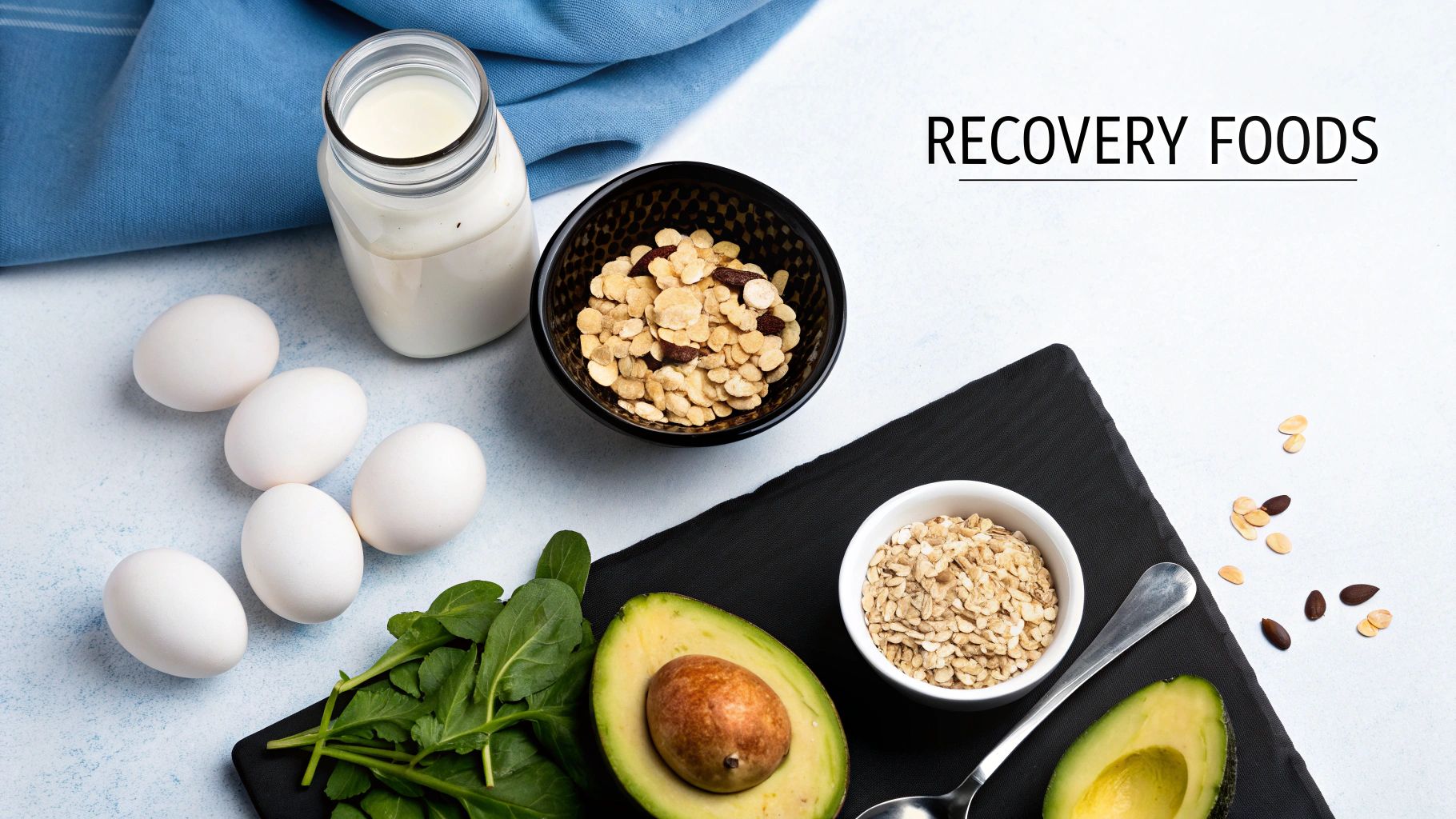 A spread of recovery foods including eggs, milk, avocado, spinach, oats, and granola on a white table.