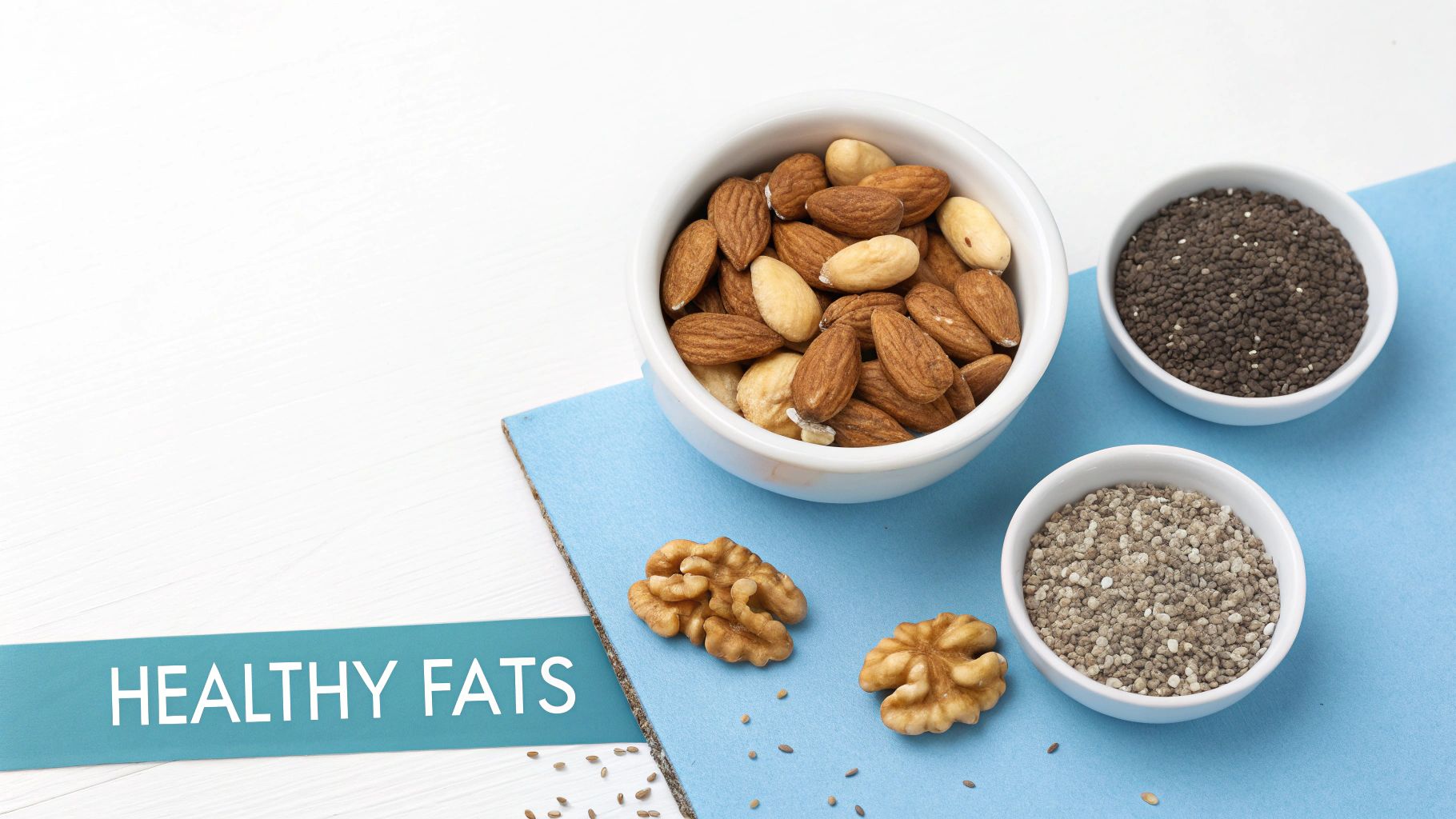 A selection of healthy fats: almonds, walnuts, and chia seeds on a blue mat with "HEALTHY FATS" text.