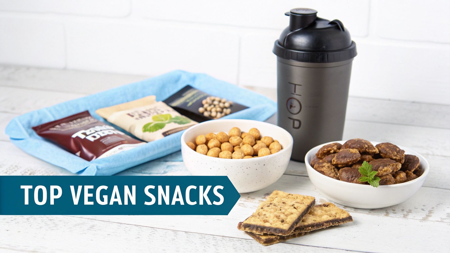 A table filled with various vegan snacks, including packaged mixes, bowls of crunchy bites, crackers, and a protein shaker.