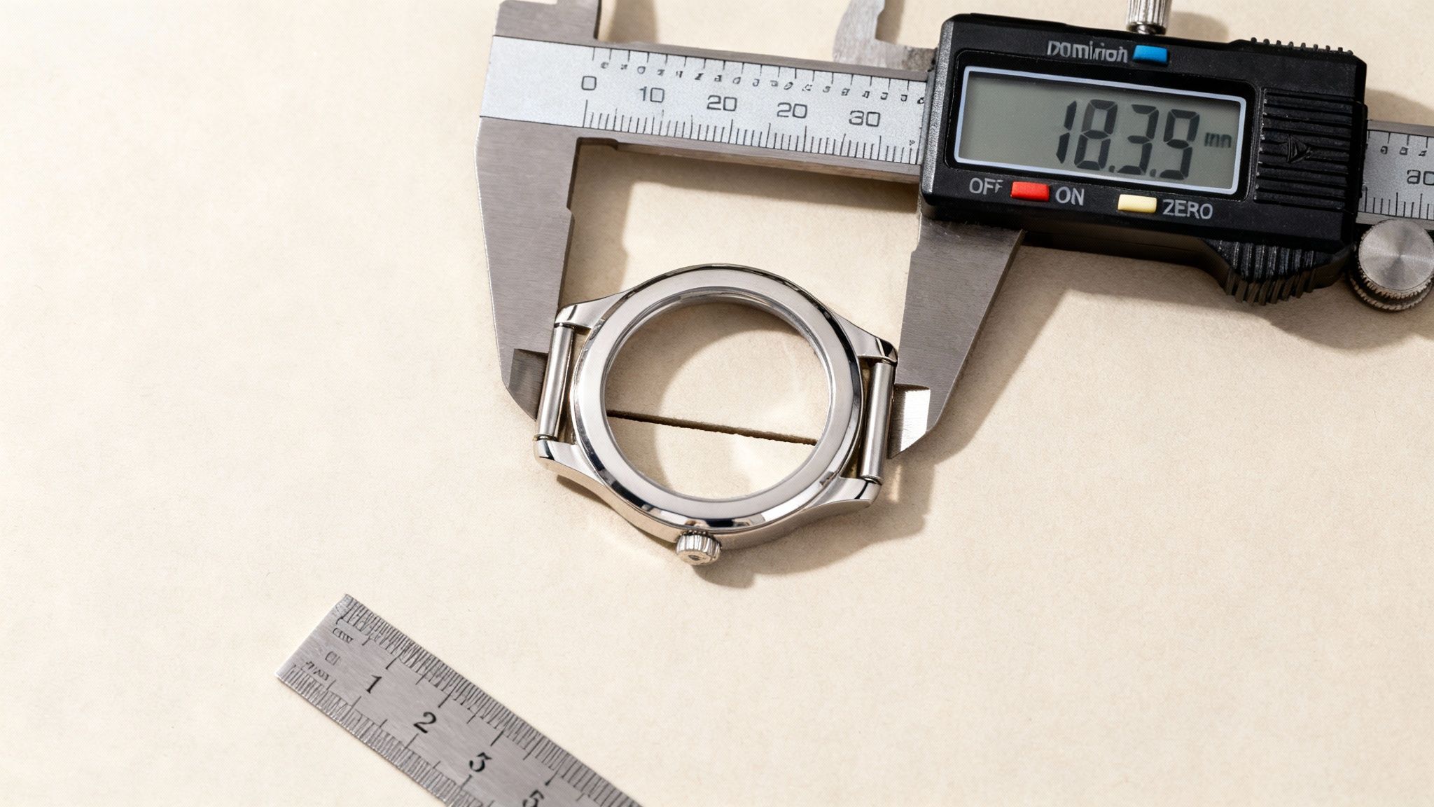 A digital caliper precisely measures the internal diameter of a shiny watch case, displaying 18.39 mm.