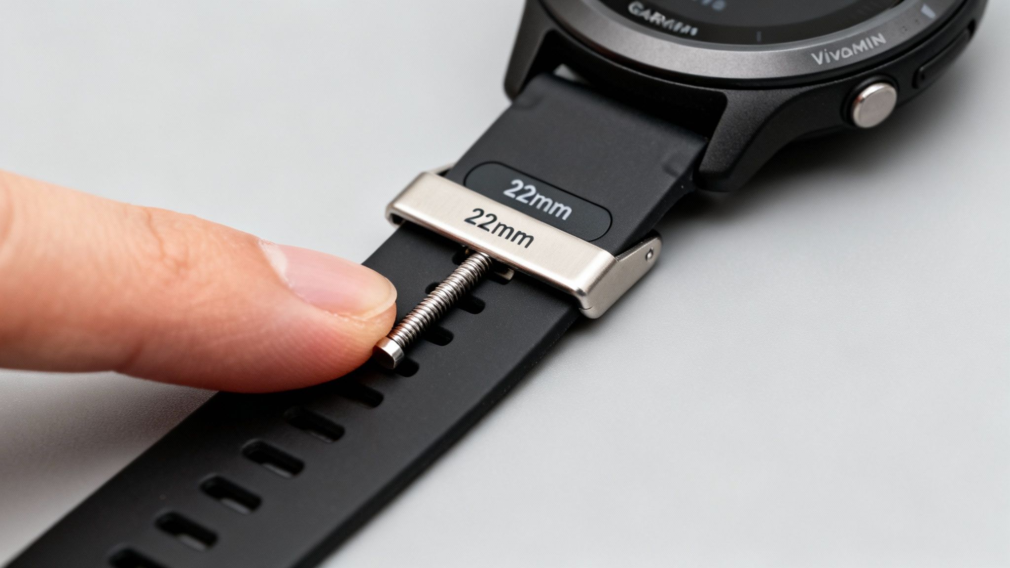 Close-up of a hand installing a 22mm black silicone strap onto a Garmin smartwatch.