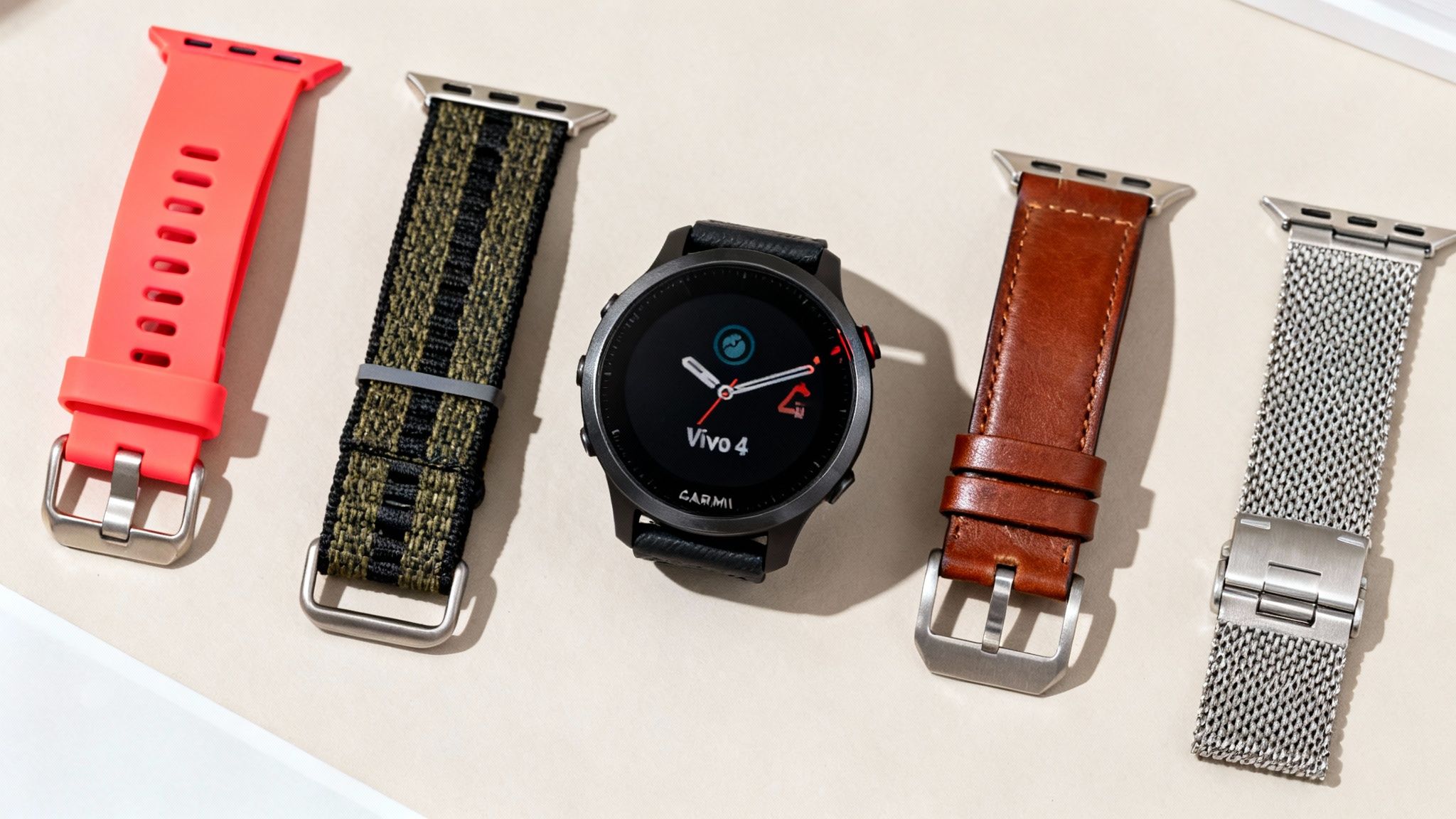 A Garmin Vivo 4 smartwatch surrounded by four different watch straps: red, green striped, brown leather, and silver mesh.