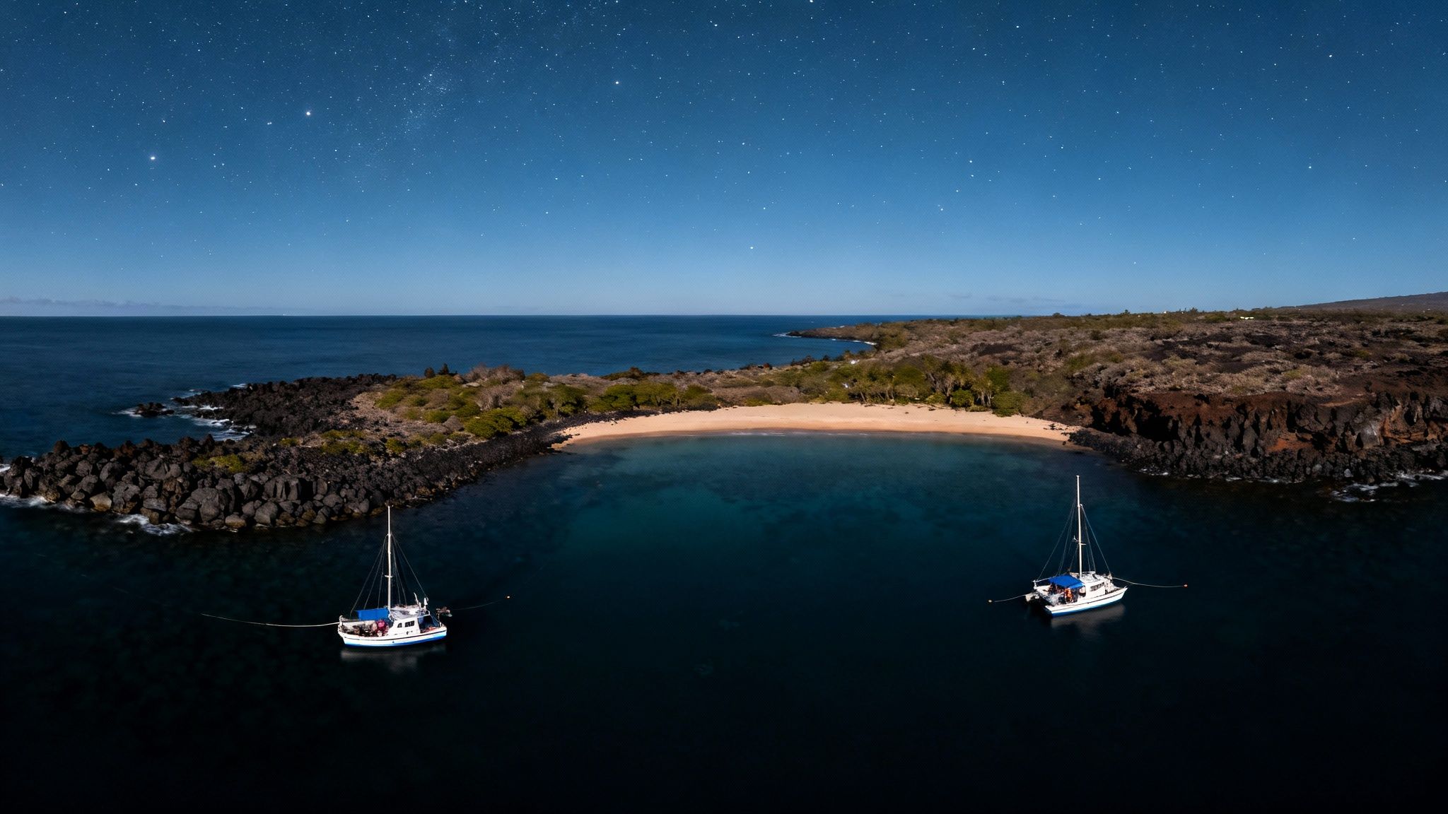 A group of divers on the seafloor at night, watching several manta rays swim overhead in Kailua Kona.