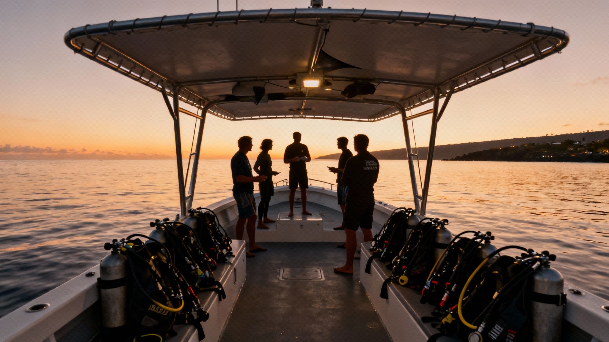 A group of scuba divers kneeling on the sandy ocean floor, looking up as a manta ray glides over them at night.