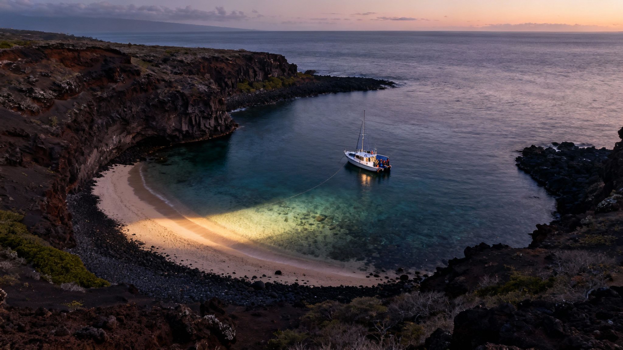 A boat shines a bright light on a sandy beach in a dark cove at sunset, surrounded by volcanic cliffs.