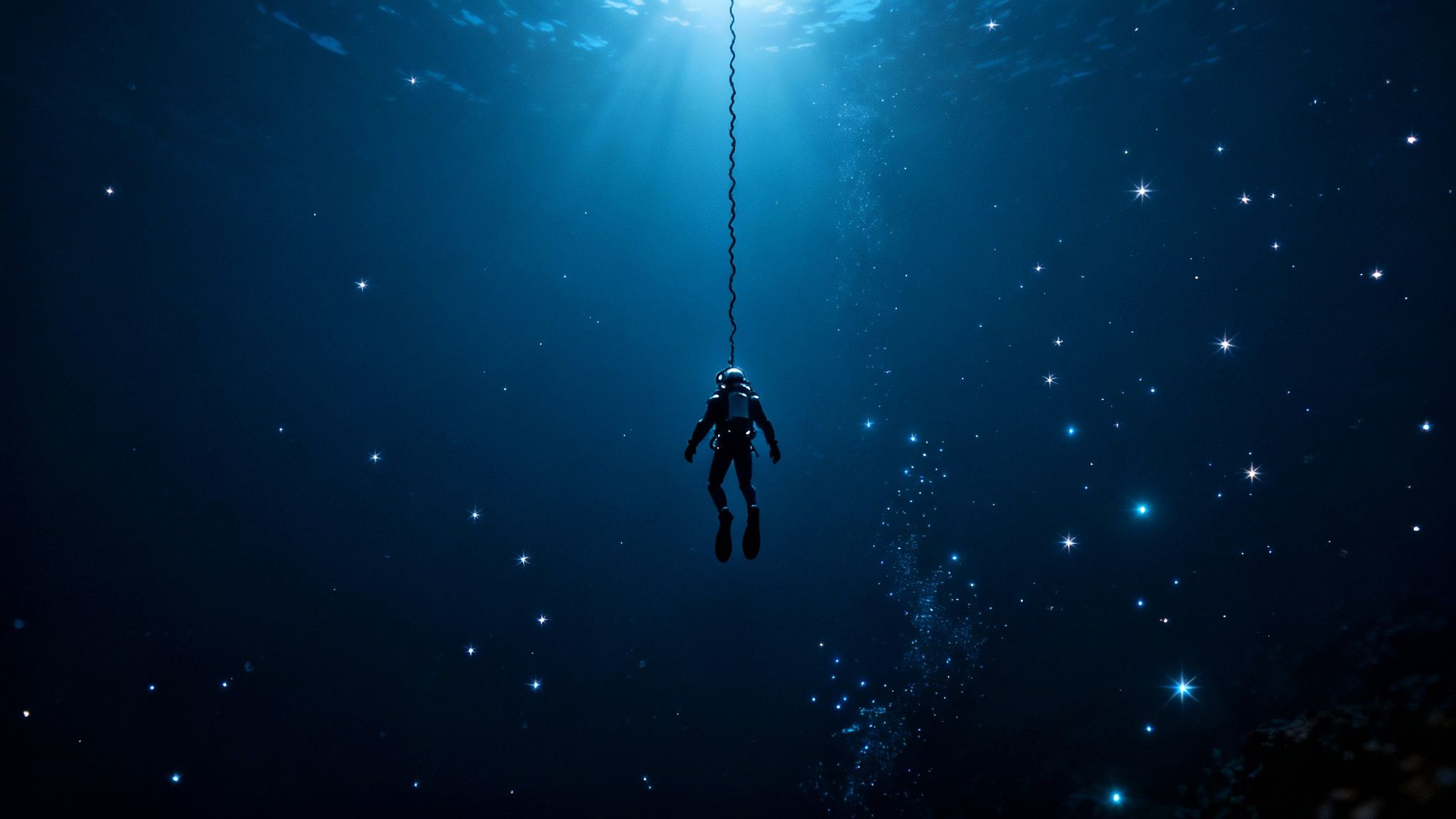 A diver shines a light into the deep, dark ocean during a blackwater dive in Kona.