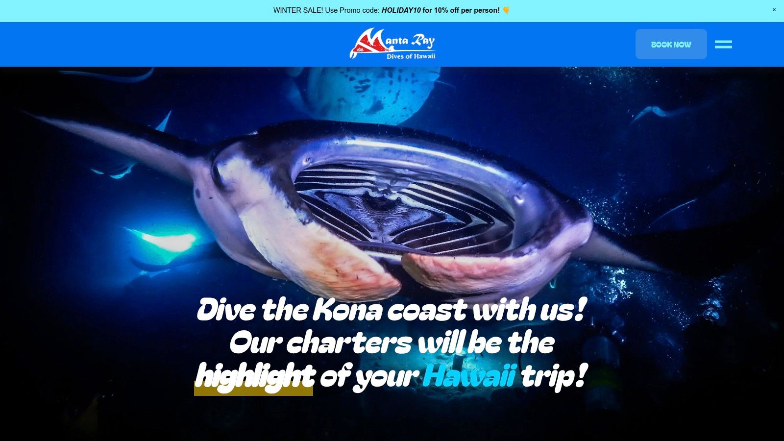 A giant manta ray glides gracefully over scuba divers during a night dive in Kona.