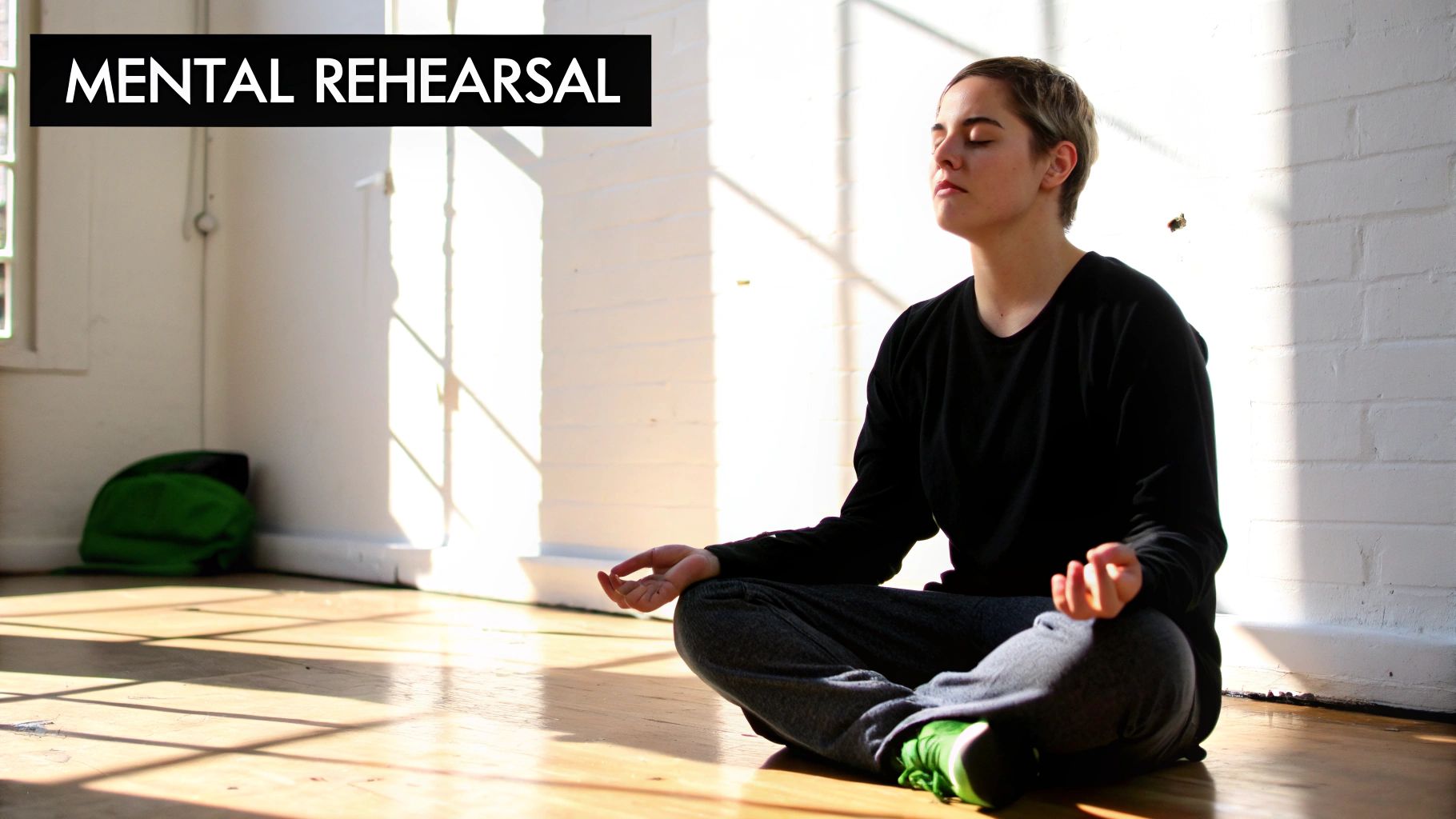 A person sits cross-legged on a wooden floor, eyes closed, practicing mental rehearsal in a sunlit room.