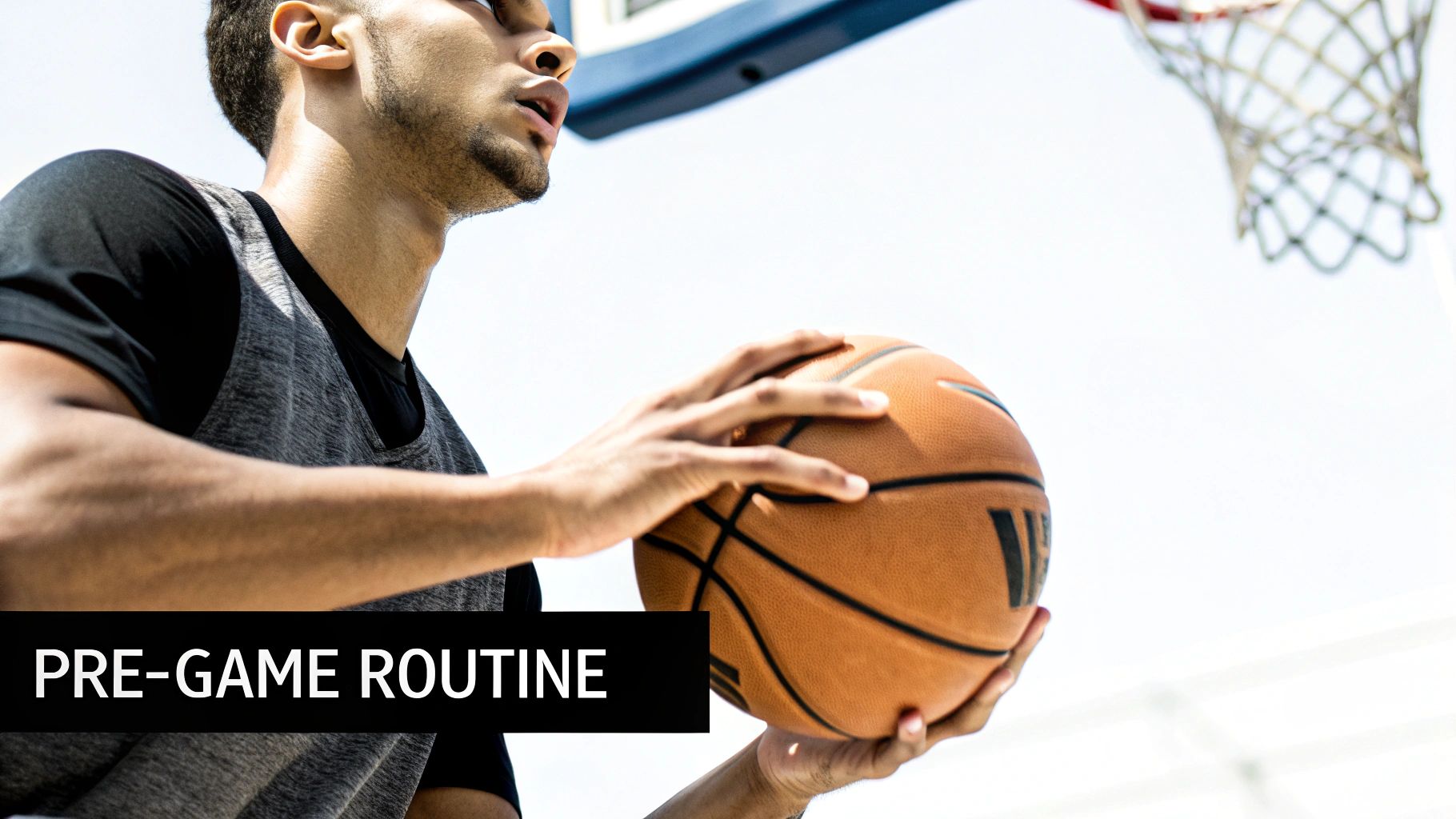 A focused basketball player holding a basketball with a hoop in the background, under a bright sky.