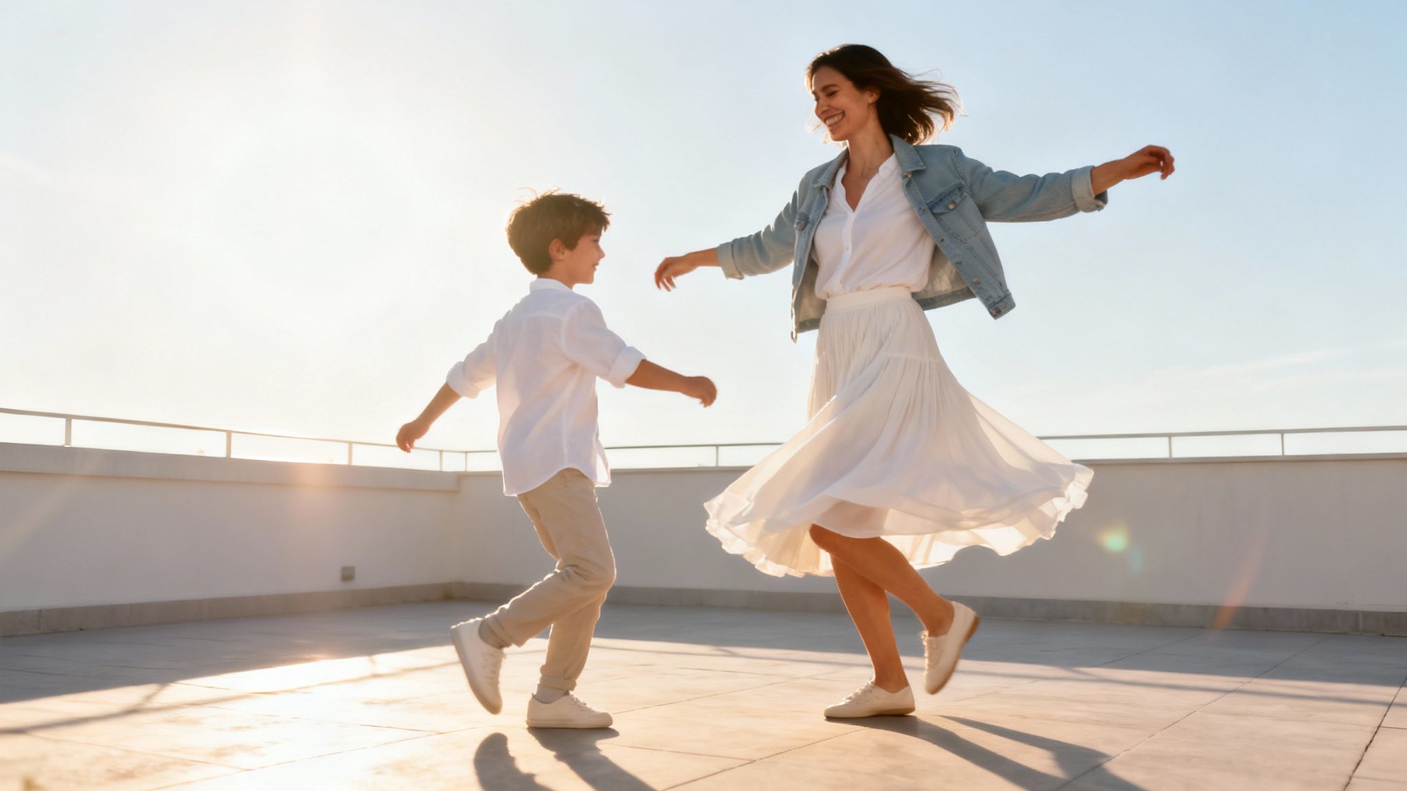 A joyful mother and son dance on a rooftop against a bright sky at sunset.