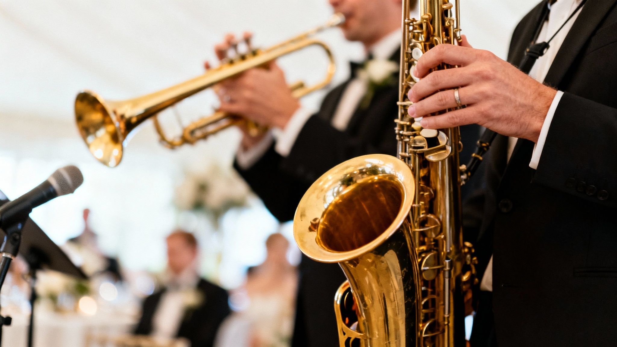 Two musicians in suits play saxophone and trumpet at a formal event with a microphone.