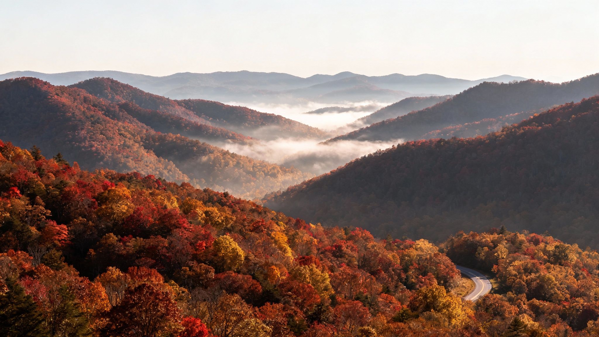 A scenic mountain range in the Smoky Mountains with vibrant fall colors and a light mist.