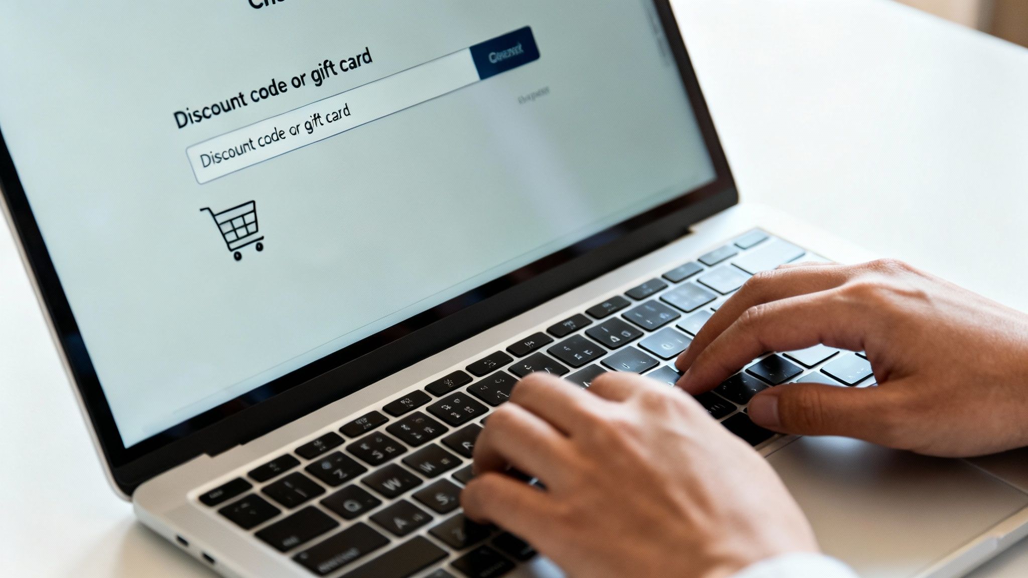 Person typing on a laptop, entering a discount or gift card code on an e-commerce checkout page.