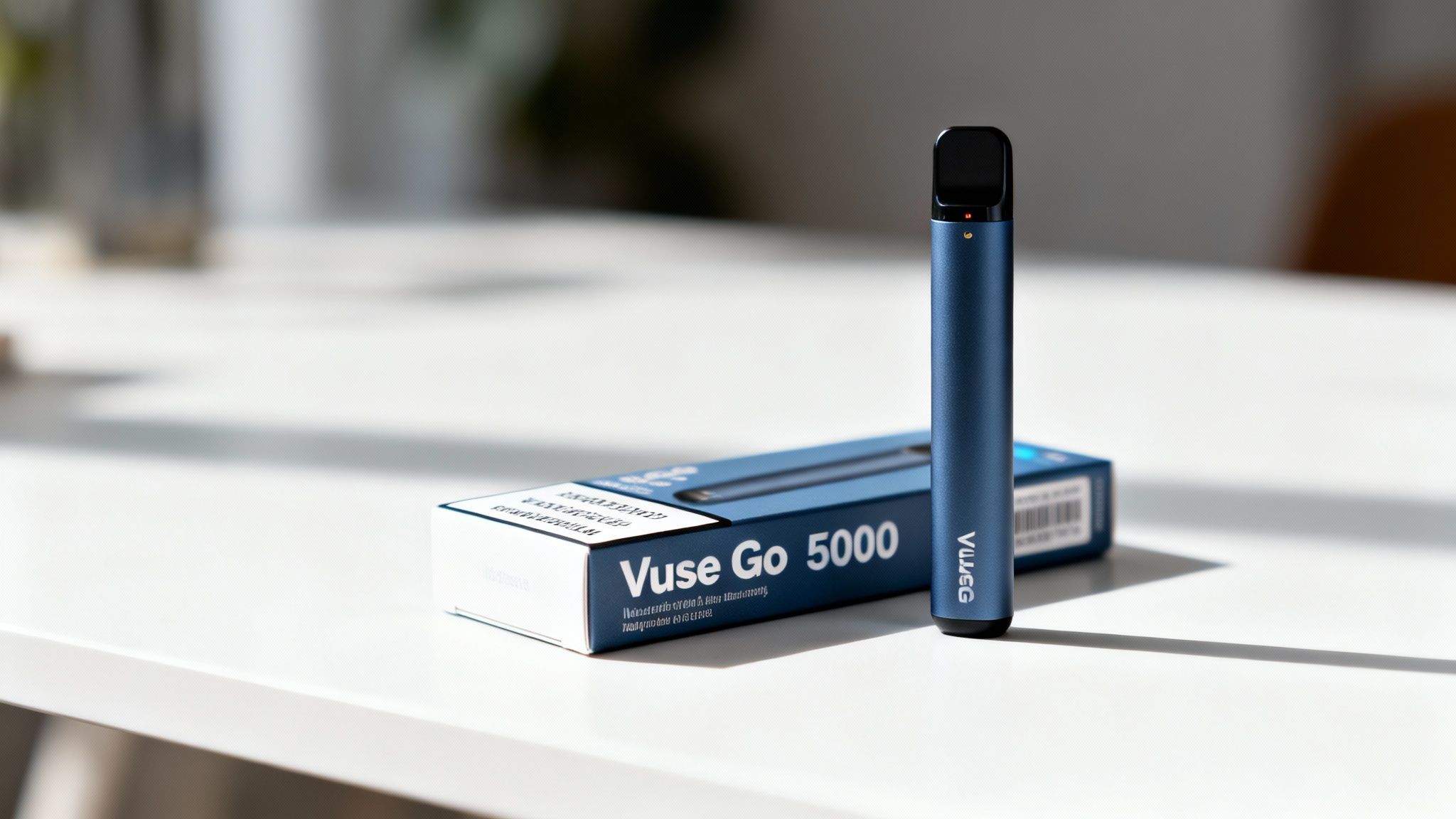 A blue Vuse Go 5000 disposable vape stands next to its matching blue box on a white table.