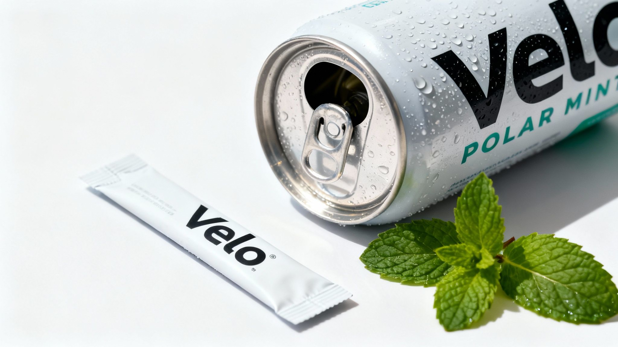 A Velo Polar Mint beverage can with water droplets, a Velo pouch, and fresh mint leaves.